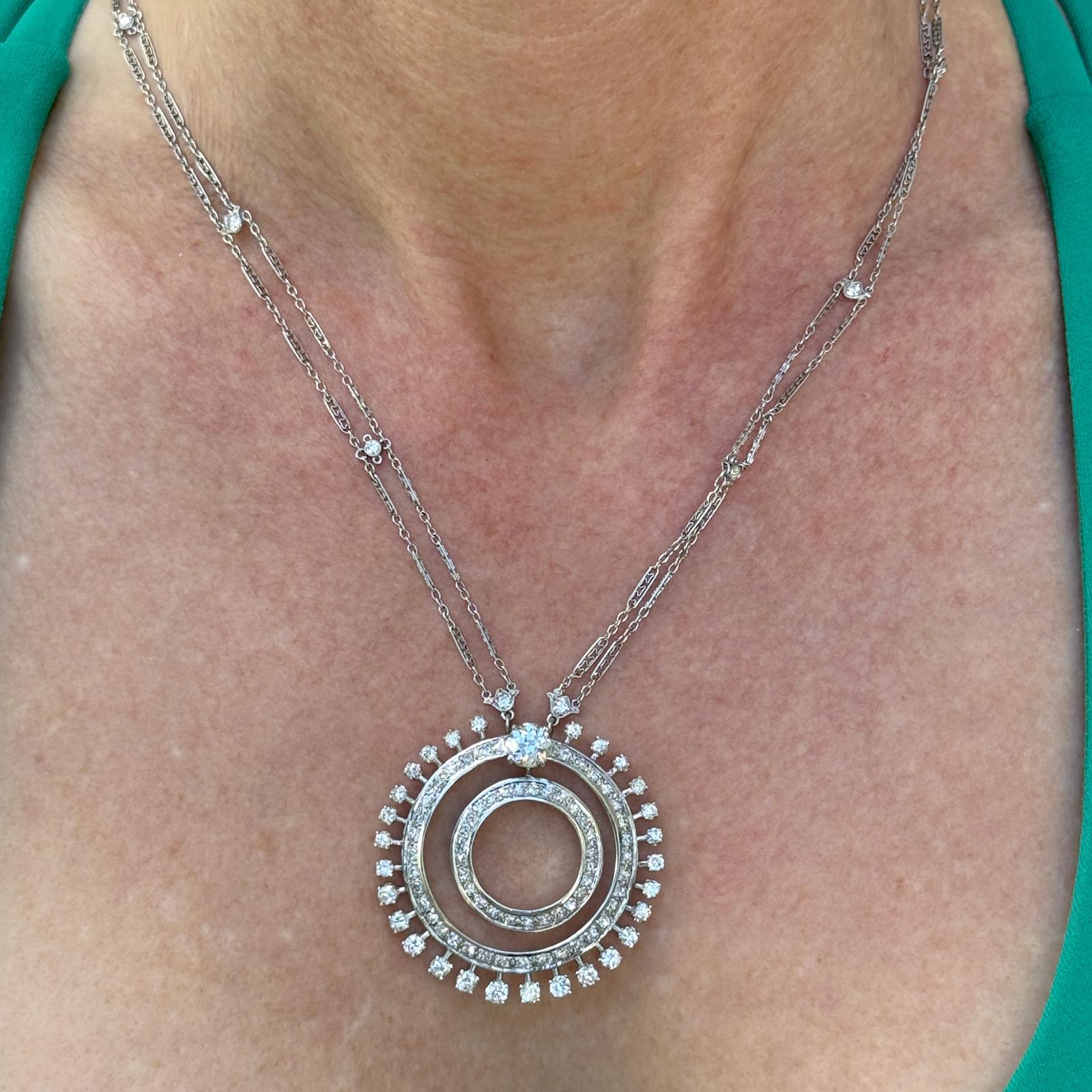 Este exquisito collar vintage muestra una elegancia atemporal y una artesanía excepcional, con un impresionante colgante circular de diamantes suspendido de un collar de diamantes de doble vuelta. El colgante y el collar están adornados con