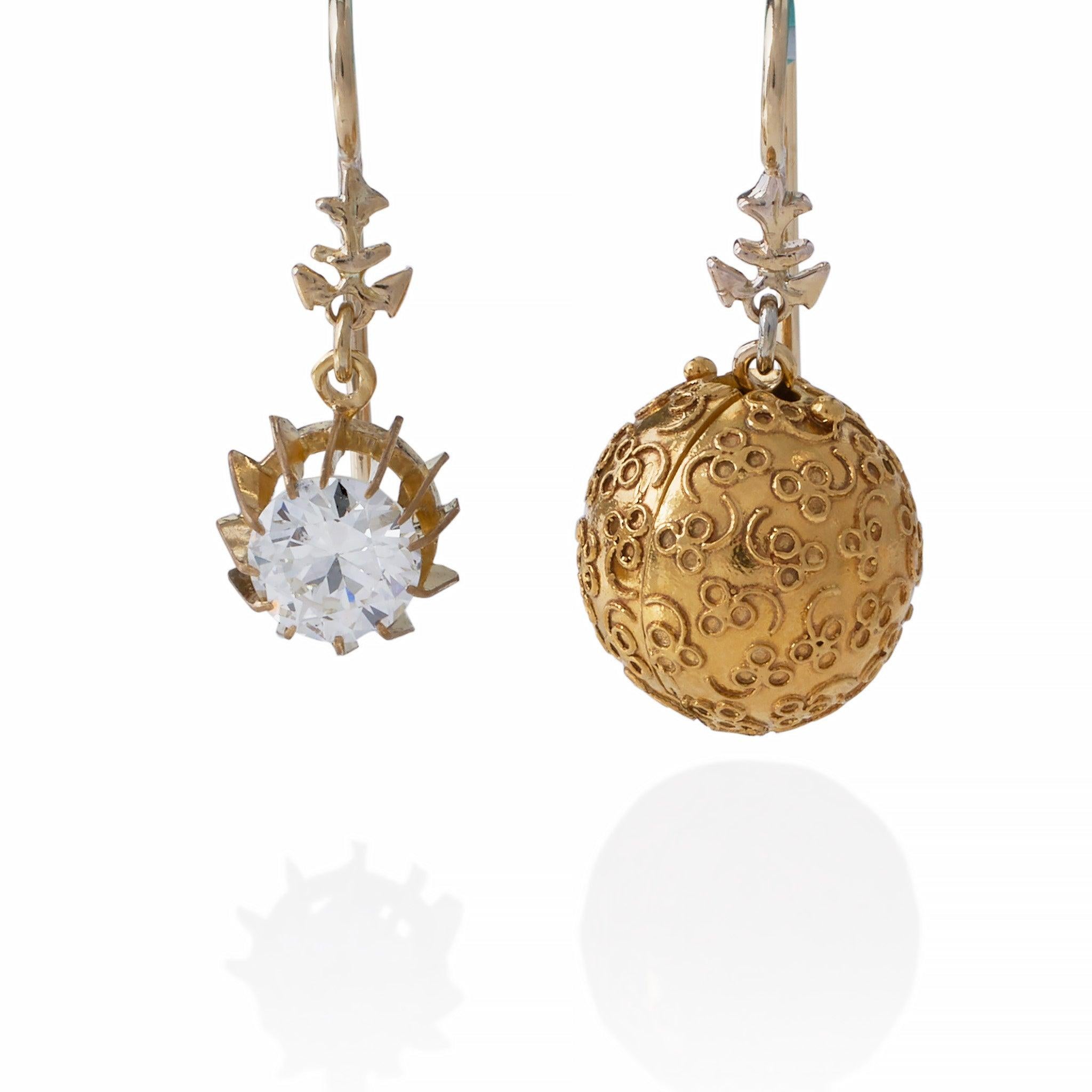 These convertible day/night pendant earrings feature old European-cut diamonds mounted in 18K gold. Each is designed as a shaped gold top suspending a removable hinged sphere with applied wirework decoration, opening to reveal a prong-set old