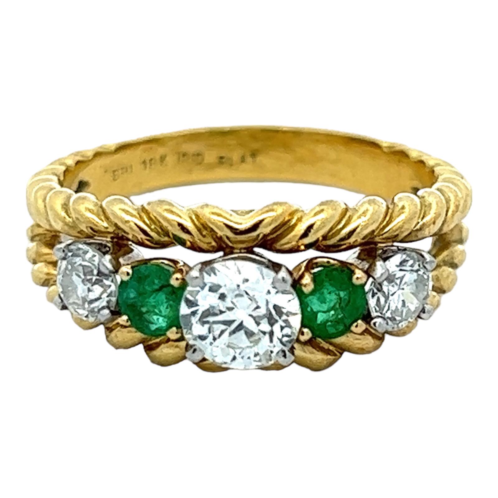 Beautiful diamond and emerald ring handcrafted in 18 karat yellow gold and platinum. The ring features 3 Old European cut diamonds weighing approximately 1.10 CTW (the center .60 CT and the sides .50 CTW). 2 round natural green emeralds are set in