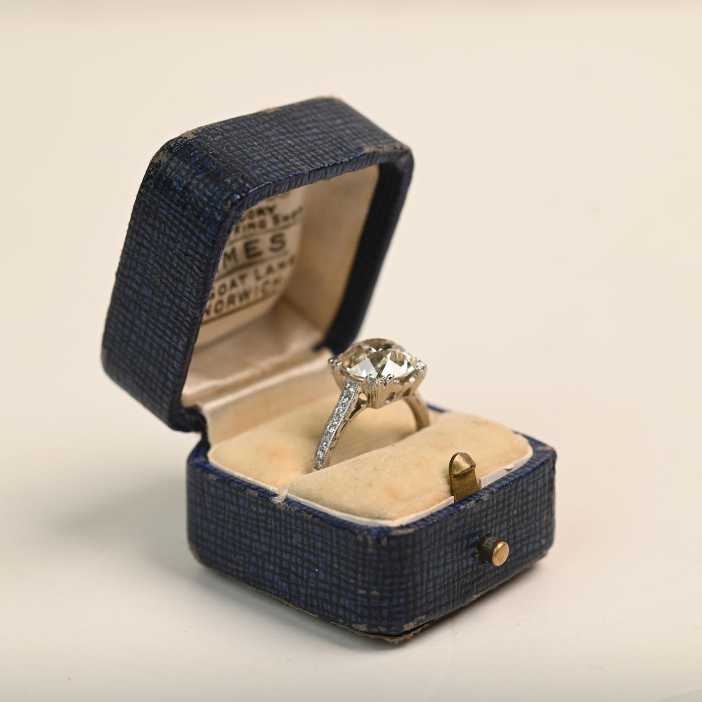 Cette bague exquise met en valeur un diamant central captivant pesant environ 4,20 carats, de couleur K et de pureté VS2. L'impressionnant diamant occupe le devant de la scène, rayonnant d'une brillance douce et élégante qui attire le regard sous