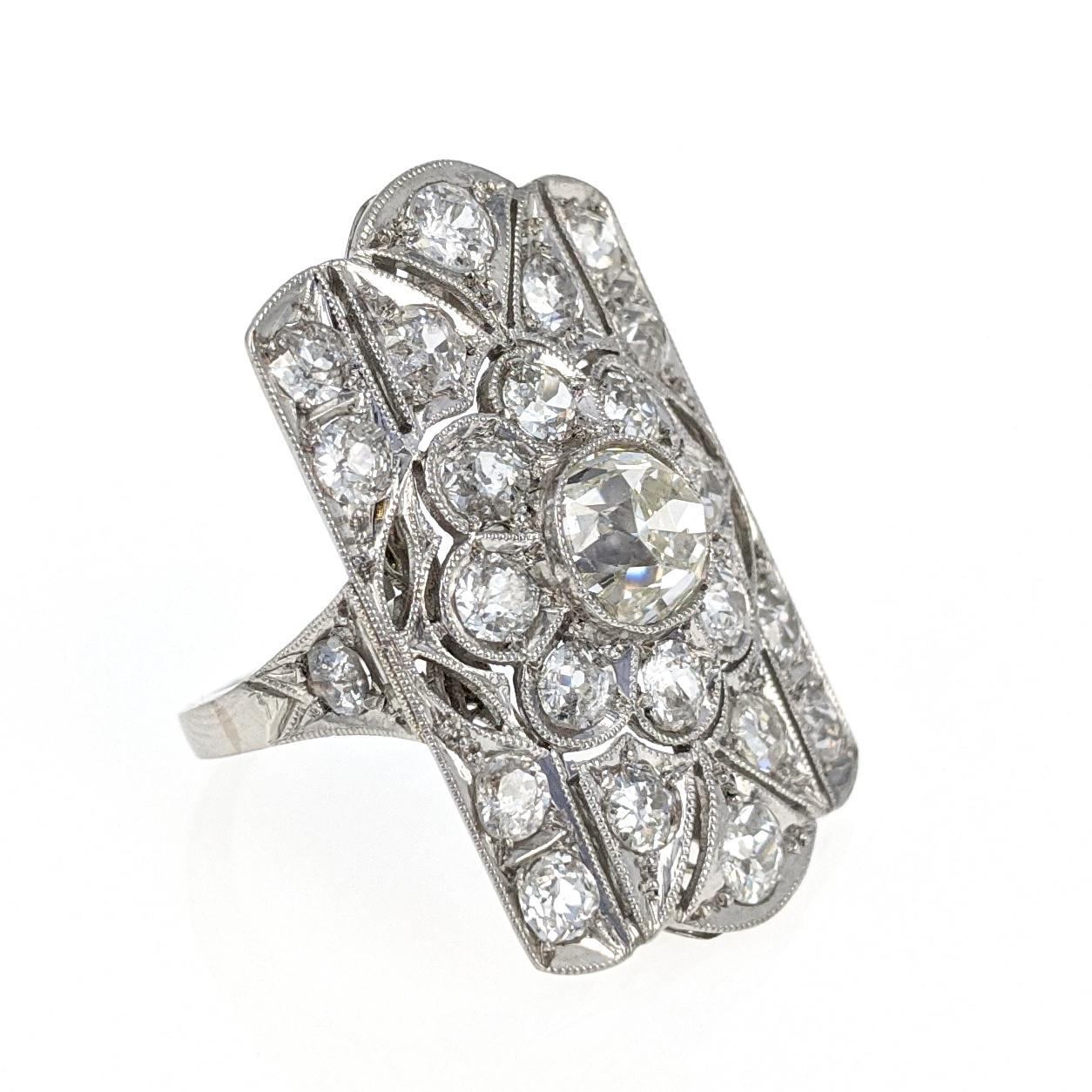 This ring centers upon nine Old European-Cut diamonds in a floral pattern. It is accented by sixteen additional diamonds for a total diamond weight of approximately 3 carats. The ring is expertly crafted in platinum with delicate milgrain details