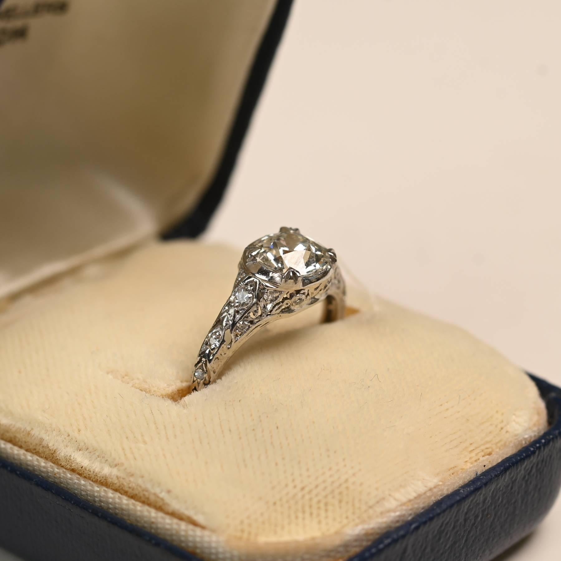 Cette bague exquise de l'époque édouardienne met en valeur un diamant certifié GIA de taille européenne ancienne pesant environ 1,10 carat, de couleur J et de pureté VS2. La pierre centrale est gracieusement complétée par un filigrane ajouré