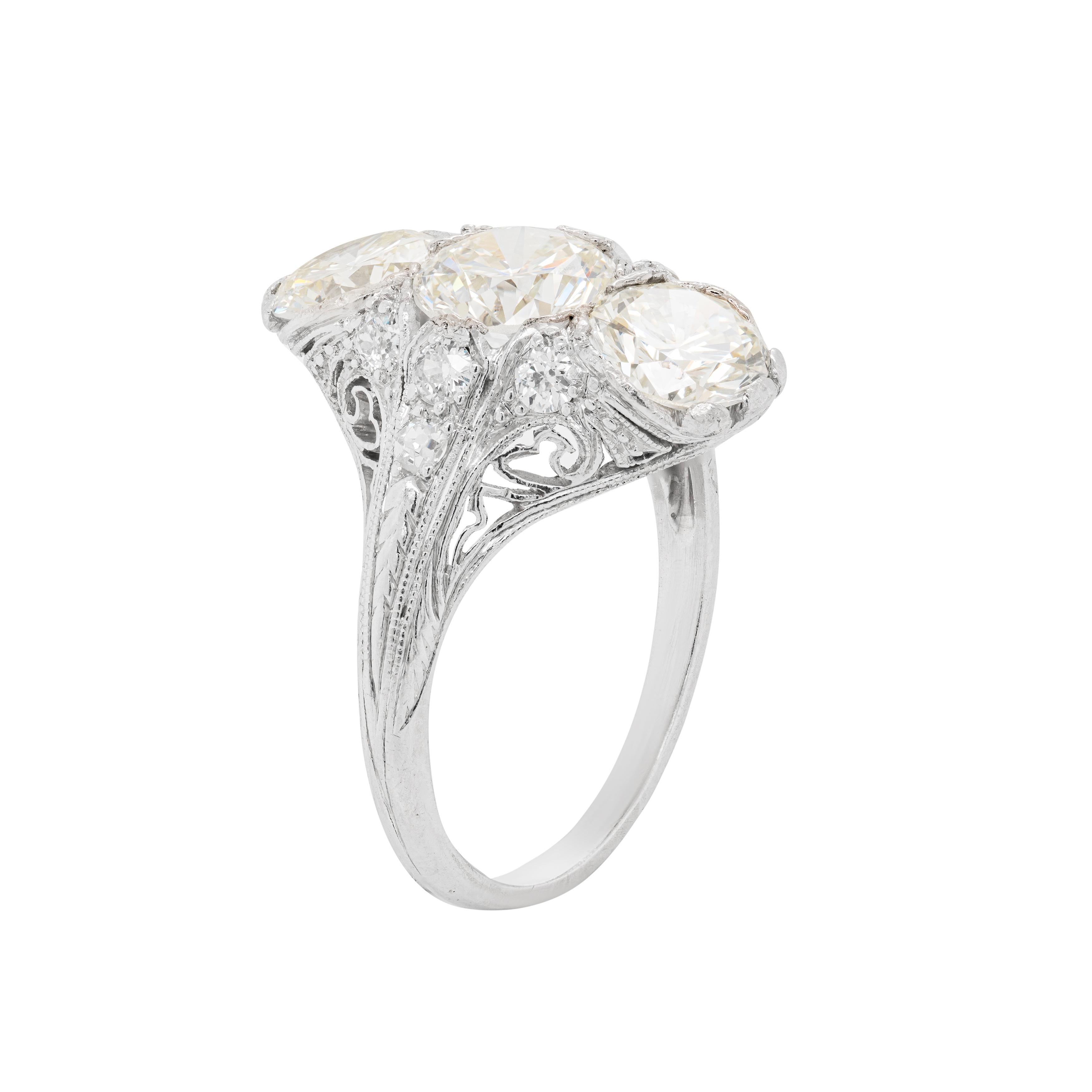 A spectacular handmade 1920's vertical three stone ring featuring 3 old European cut diamonds  totalling to an approximate weight of 3.50ct. These stones are set in a beautifully intricate filigree open work mount further accompanied by four old cut