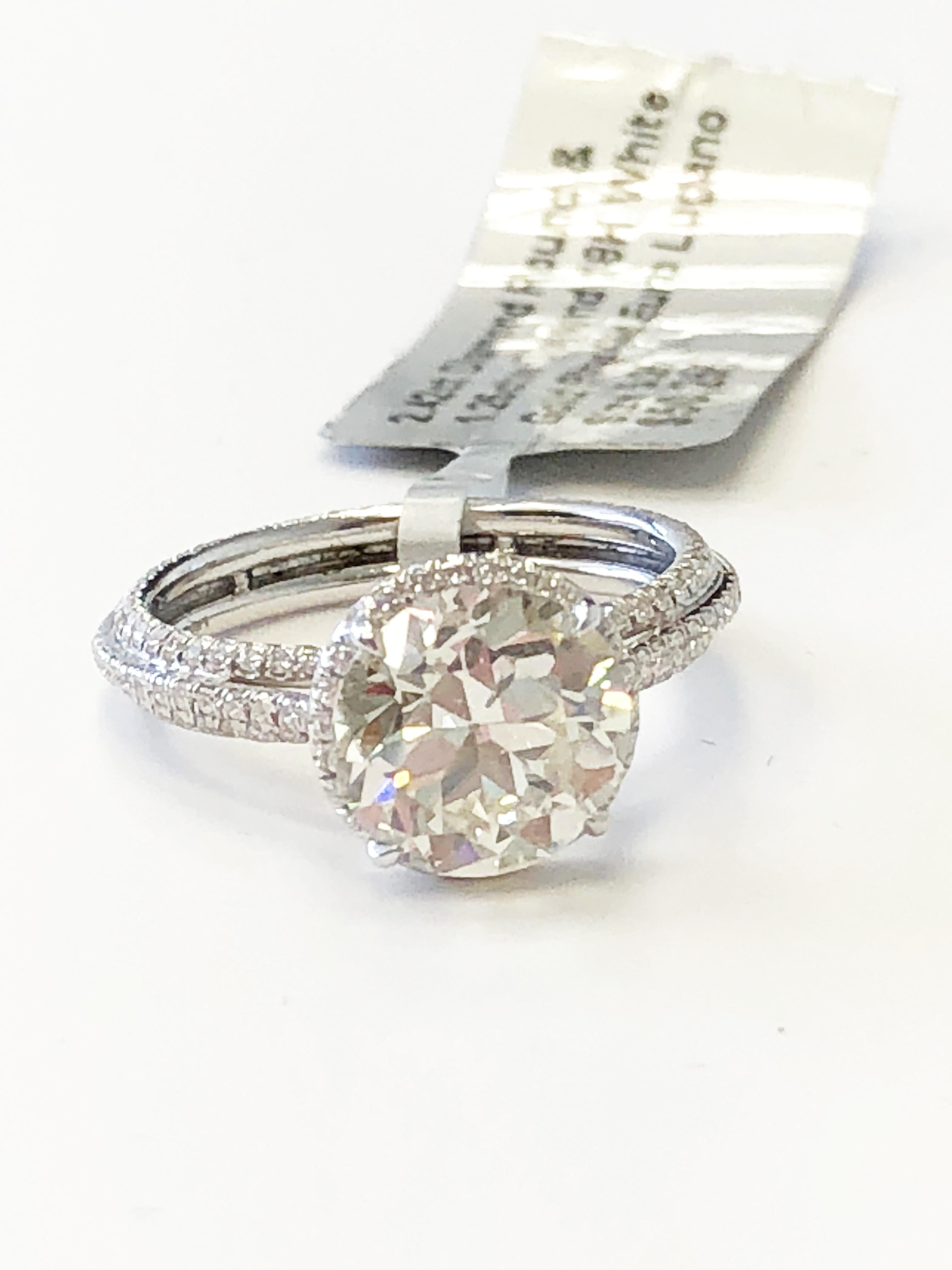 2.42 carat old European round cut diamond surrounded by 1.25 carats of white diamond rounds in a 18k white gold mounting size 5.25.  This ring is stunning and would work perfectly for an engagement ring!  Ideal for someone who appreciates old