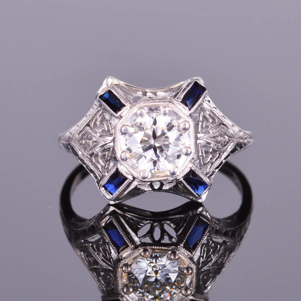 This ring is gorgeous and has a distinct antique look! With a beautiful .77 carat old European cut diamond accented with deep blue sapphire baguettes, all set in 18k white gold.  Size: 7.75   Weight:  3.1 grams