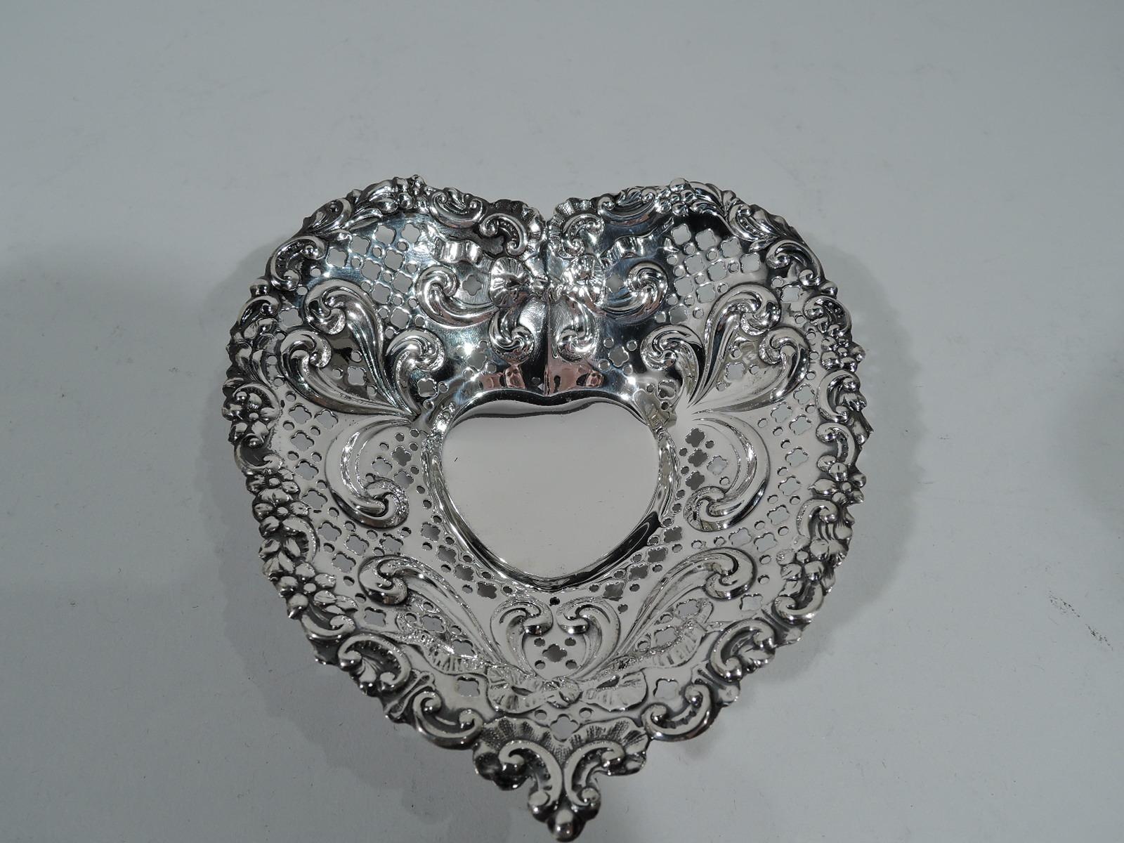 Charming old-fashioned sterling silver heart dish. Made by Gorham in Providence. Solid well and wide tapering sides with embossed bow-tied ribbon and scrolls and pierced circles and quatrefoils. Irregular rim with scrolls and flowers. Three ball