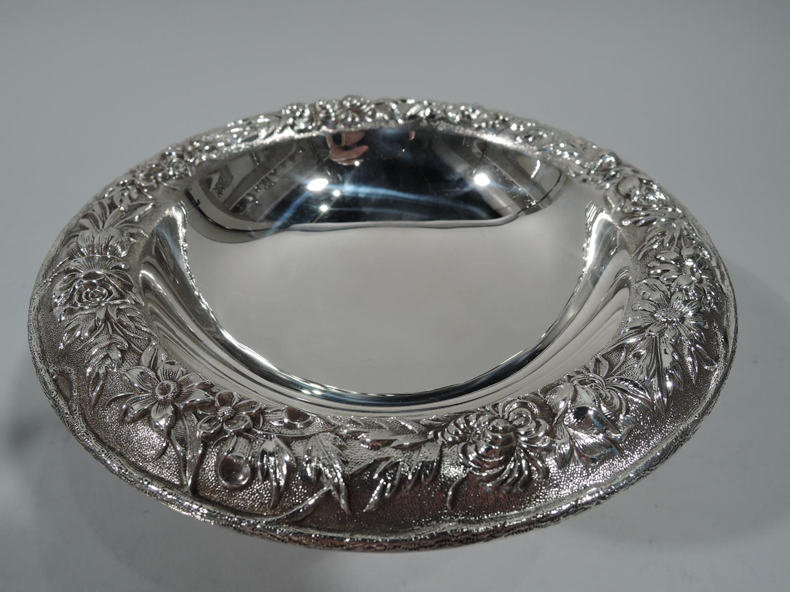 Old fashioned sterling silver compote. Made by S. Kirk & Son in Baltimore. Deep round bowl with curved rim, spool support, and stepped round foot. Rim has repousse floral garland on stippled ground. Hallmark (1932-61). Number 436. Weight: 6.4 troy