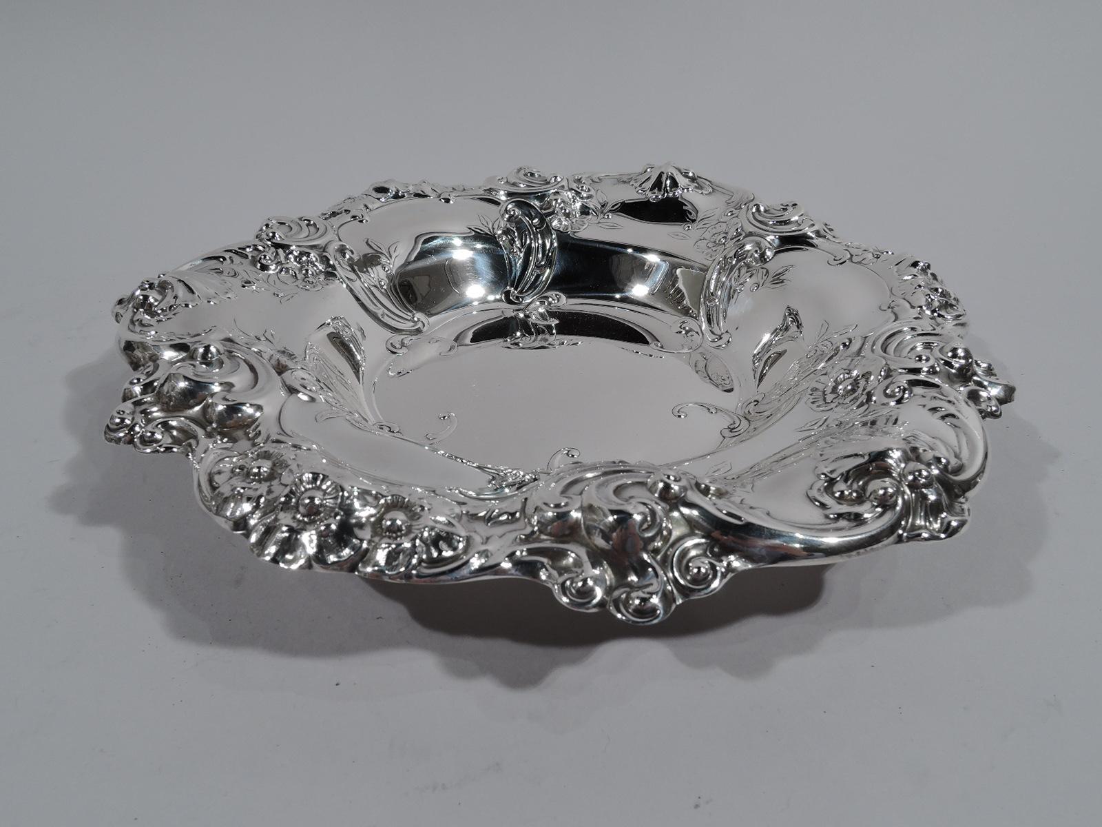 Old-fashioned sterling silver bowl. Made by Gorham in Providence in 1955. Round well with tapering sides and scrolled rim. Embossed shells, scrolls, and flowers. Pretty and tactile. Fully marked including date code and no. 818. Weight: 16 troy