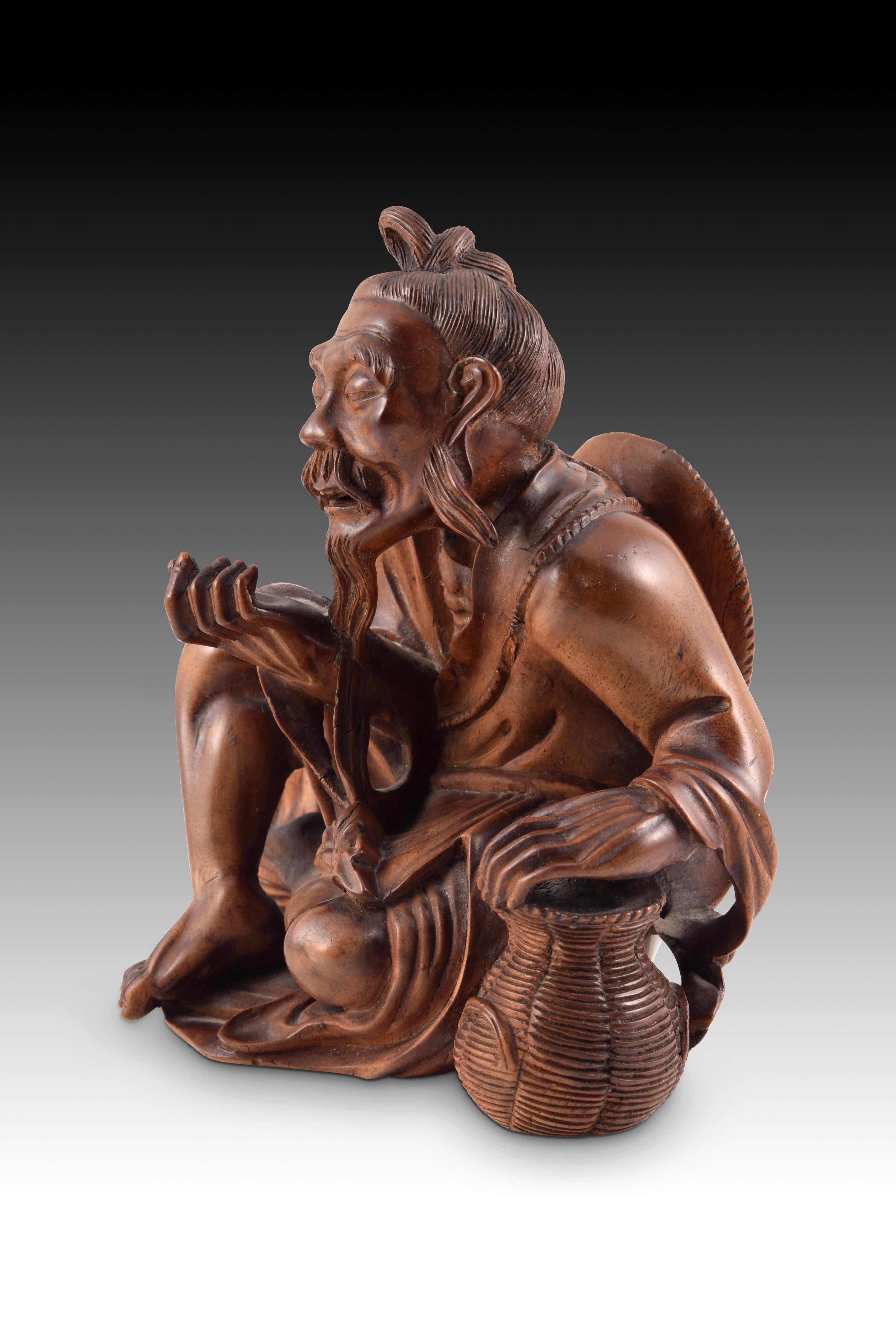 Old fisherman, oriental carving. Wood. Twentieth century. 
Carving made of wood in its color that shows an old man seated, with a basket to one side, a cloth in his hand and a circular straw hat on his back. This type of work was very common in the