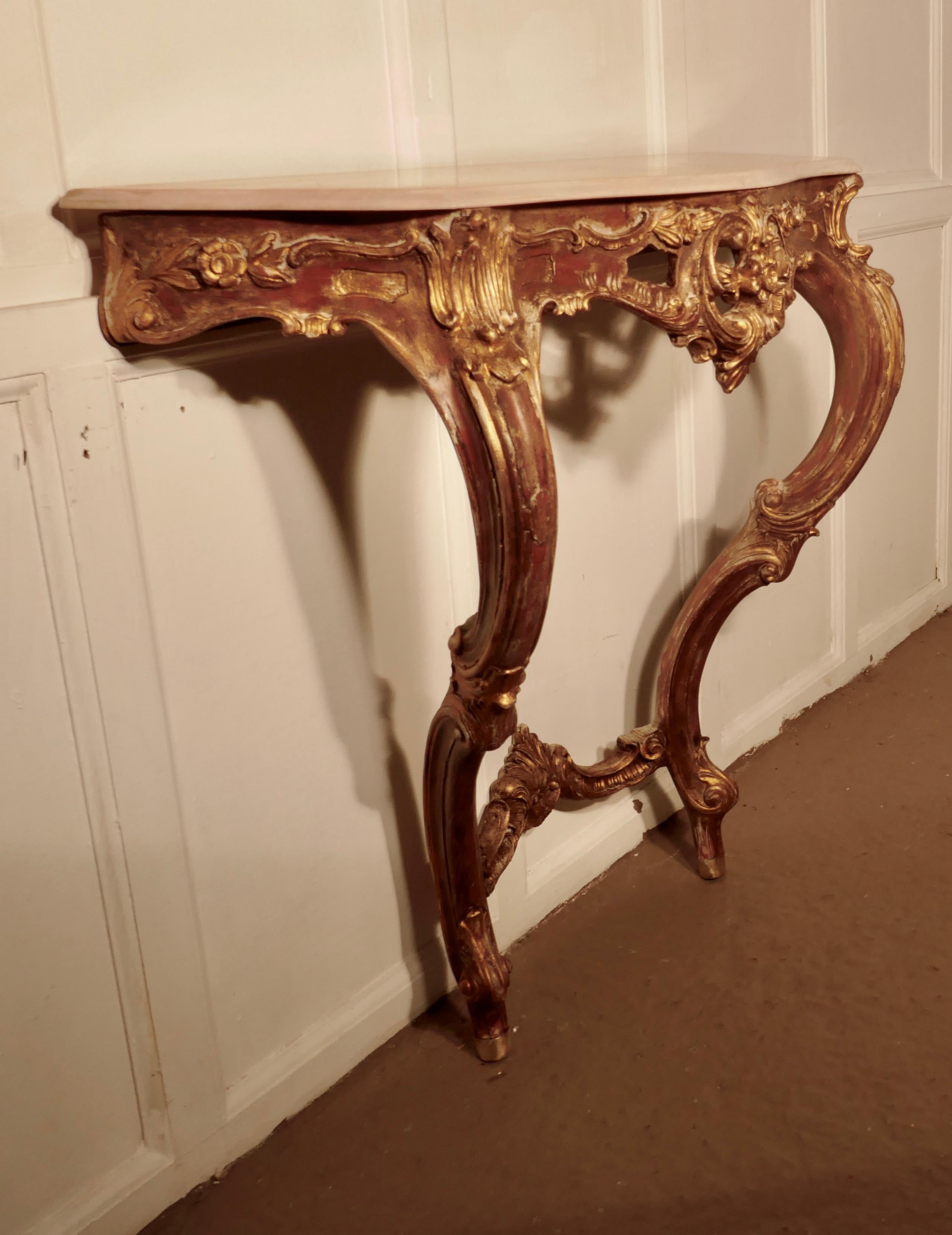 Old French gilt console or hall table

This is a very attractive piece, the table has decorative scroll and shell decoration, both to the legs and to the freeze
The tabletop is a scalloped shape with a moulded edge to carry the peach colored