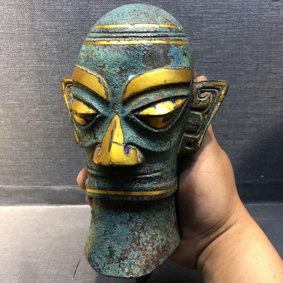 Sanxingdui is an ancient cultural site that dates back to the Bronze Age, the Sanxingdui Head is a gilt bronze statue head that is believed to have once been part of a full-bodied figure. It is one of the most striking and enigmatic pieces found at