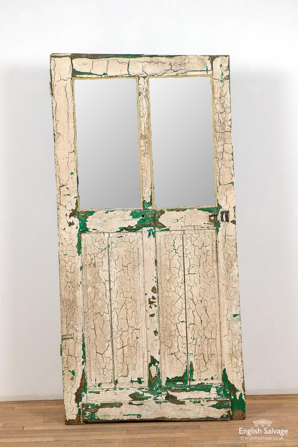 Old interior door with two panels with glass above two fielded panels. Slice added to top, handle, lock and nail holes present, plus and uneven bottom rail.