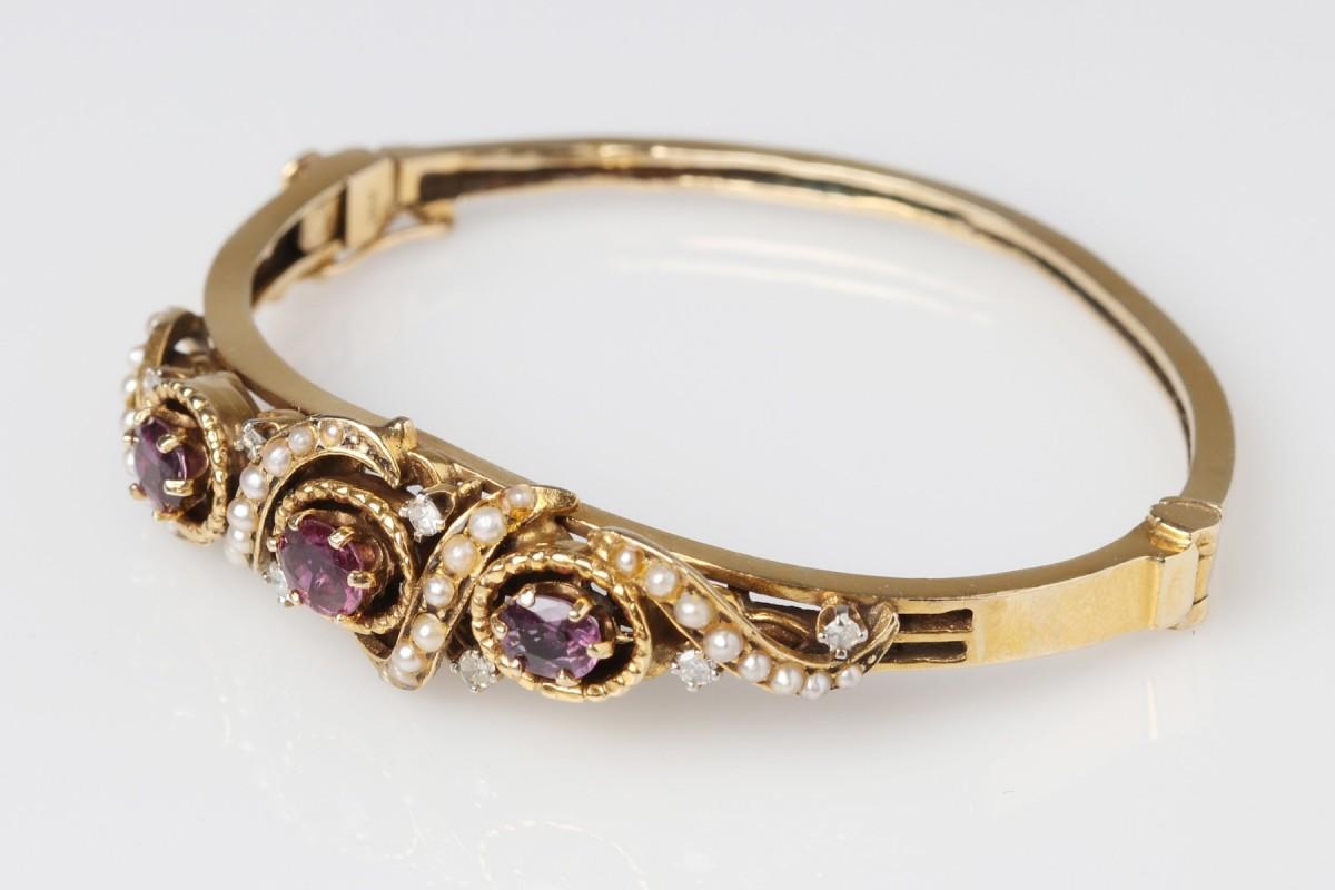 Ein altes starres Armband aus 14-karätigem Gelbgold (Feingehalt 0,585), besetzt mit Rubinen, natürlichen Perlen und Diamanten.

Herkunft: Skandinavien, Anfang des 20. Jahrhunderts.

Das Armband ist mit drei natürlichen Rubinen verziert, zwischen