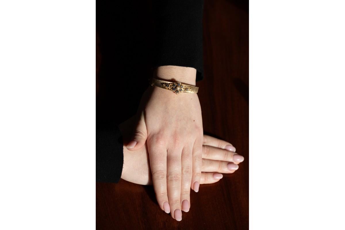 Bracelet rigide ancien en or jaune mat 14 carats

L'élément décoratif du bracelet est un ornement en forme de fleur filigranée composé de 8 saphirs d'un poids total d'environ 0,50 ct et d'une perle de culture. Cette fleur est entourée de détails