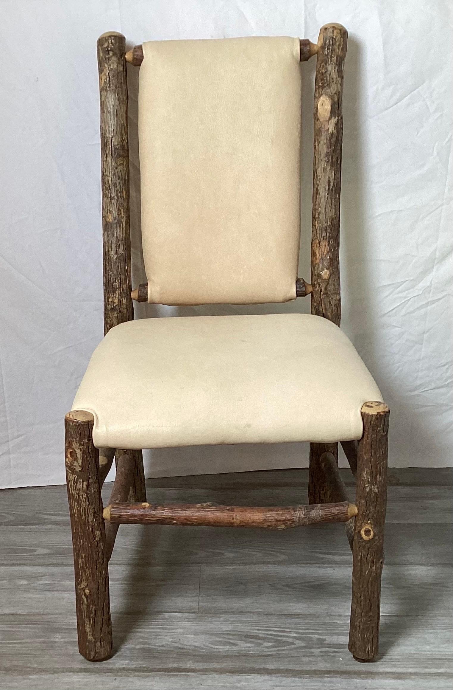 An Old Hickory side chair with deer skin seat and back. The hickory wood frame with natural bark with a light finish over the surface. The seat and back in natural color deer skin. Marked with label. Old Hickory, Shelbyville IN.