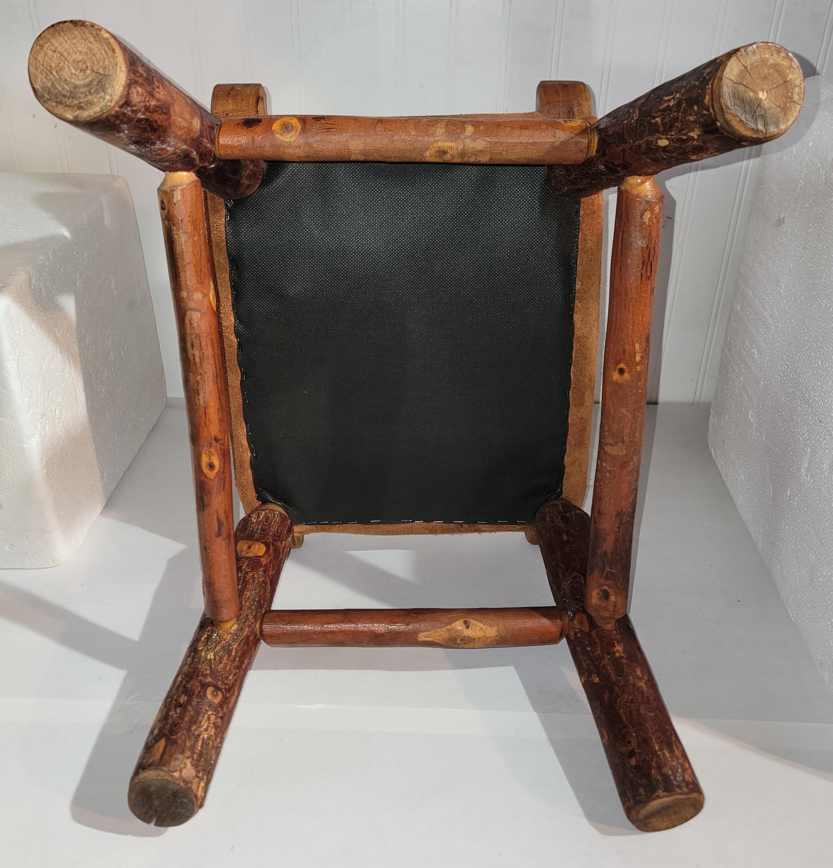 Early 20Thc Old Hickory foot stool with a fine aged patina.The top seat is suede and newly upholstered ( leather ). The condition is very good and sturdy.