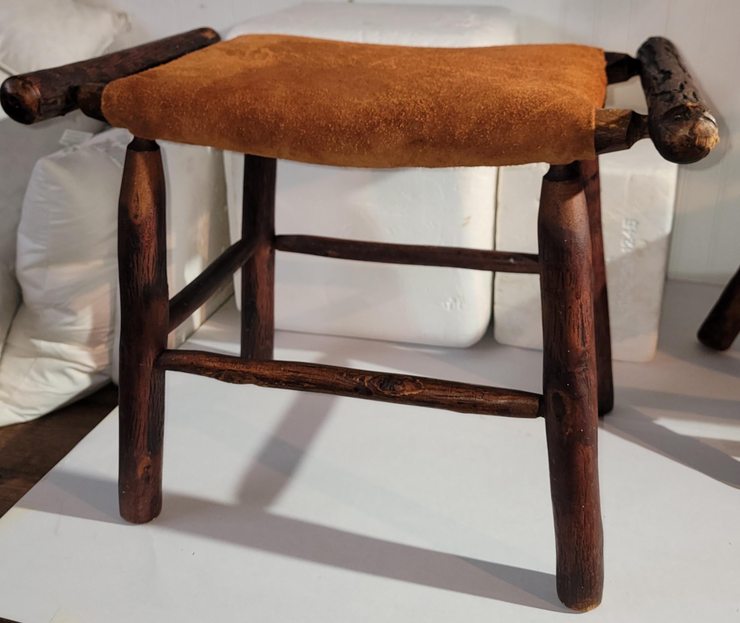This Old Hickory double handled foot stool or ottoman is in fine as found condition.The top or seat is in a brown suede ( leather ) and has a wonderful aged patina.
