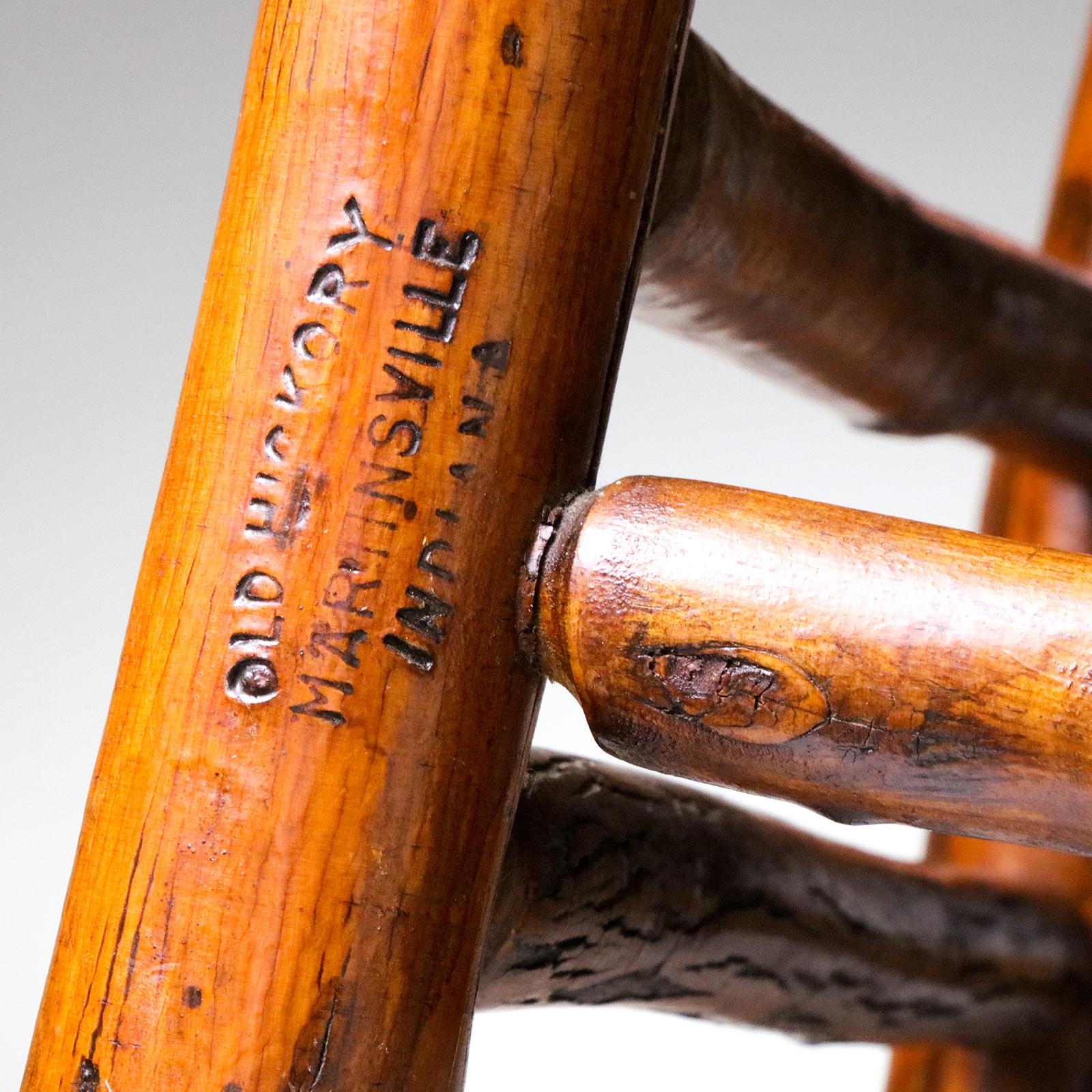 Mecedora vintage de madera de nogal americano de la Old Hickory Company de Martinsville, Indiana. El asiento y el respaldo están tejidos a mano en el tradicional estilo de trabajo de caña abierta. Esta silla Adirondack es típica del estilo visto en