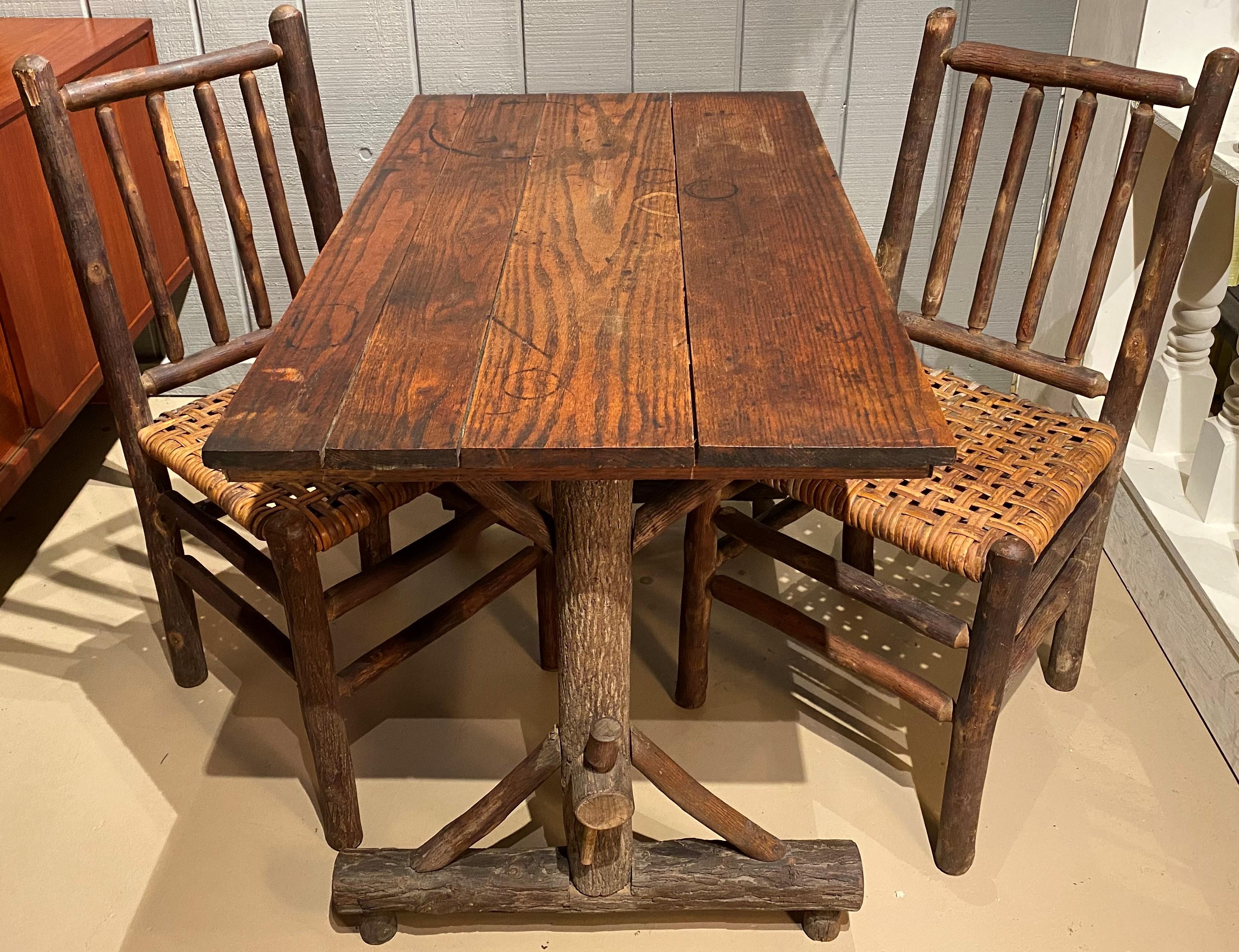 A fine rustic midcentury Davenport form table with two matching side chairs with rattan seats by Old Hickory, Martinsville, IN. The table features a three oak board top and is signed with the Old Hickory Martinsville Indiana brand on the single
