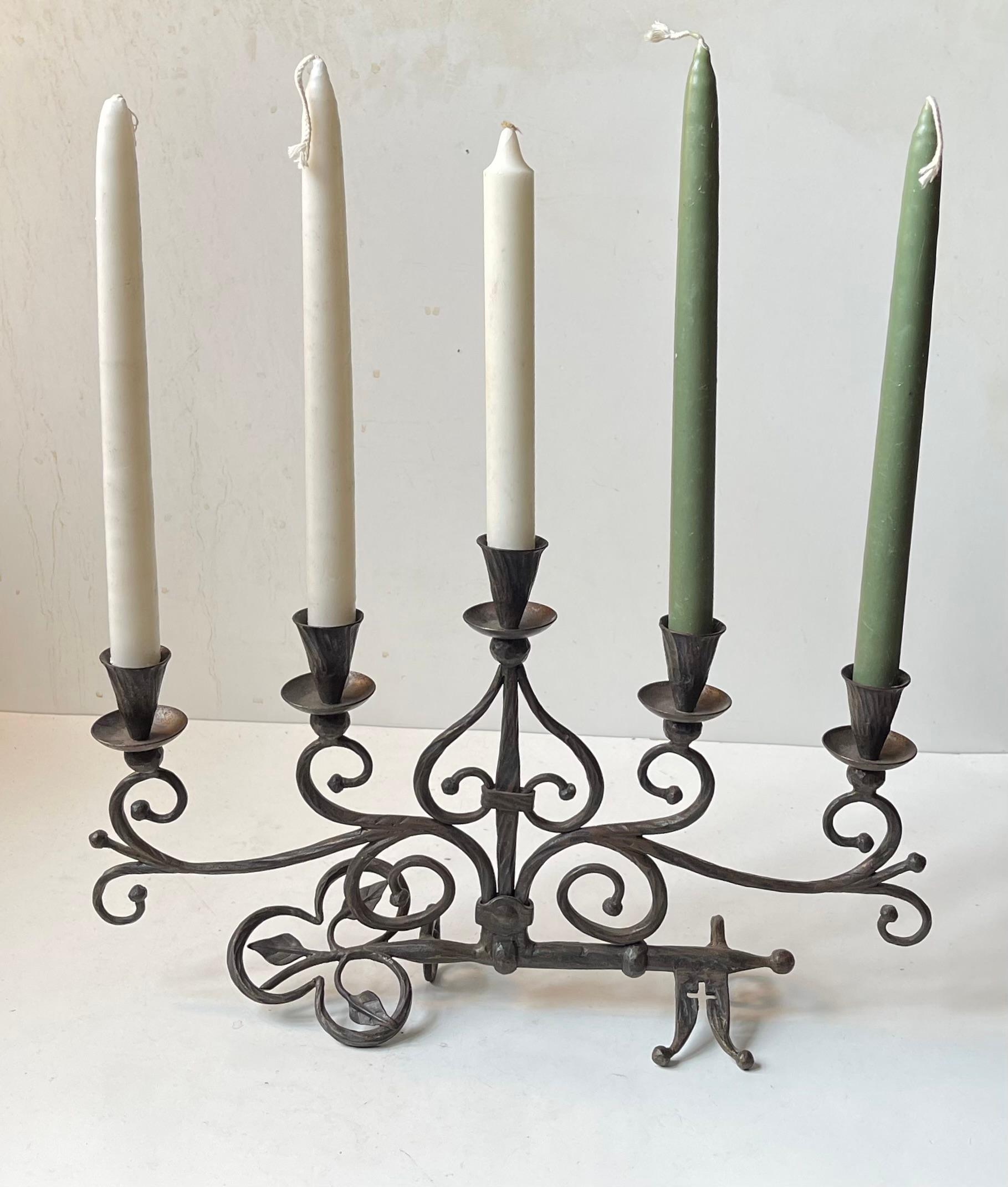 An unusual hand-forged church or cathedral candelabra made from an old partially modified large church key that functions as its base. The leaf-work and twists to the wrought iron resembling branches are very art nouveau in style. Whether or not