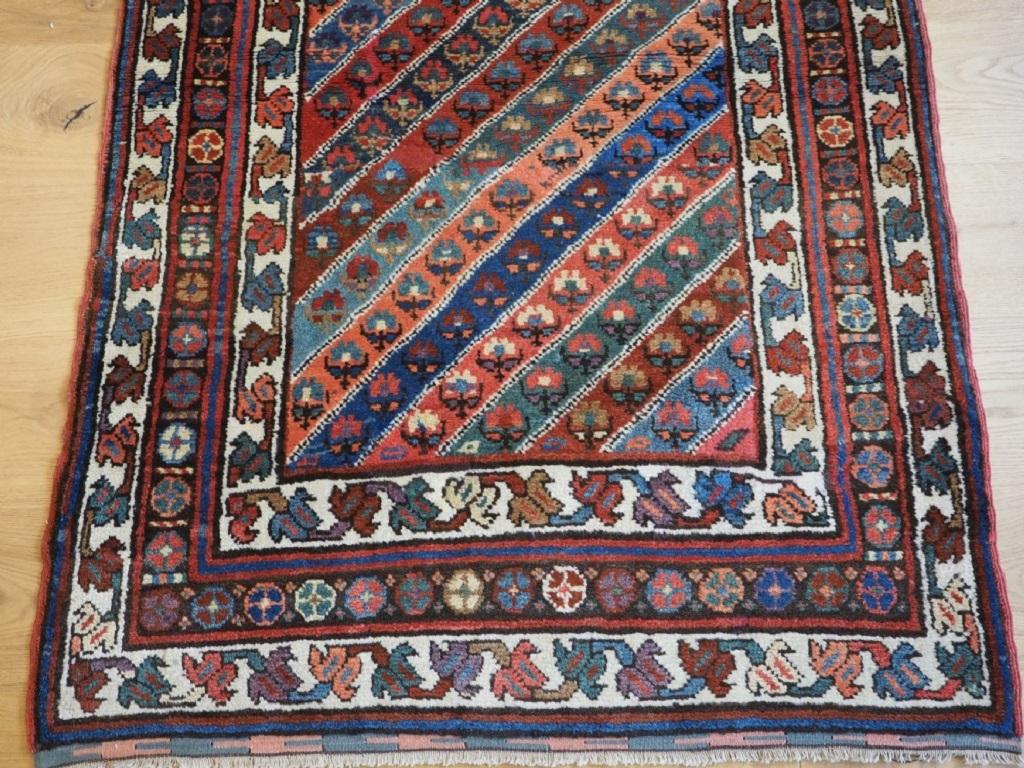 Alter südkaukasischer Kurdenteppich mit buntem Diagonalstreifenmuster
Um 1930

Es handelt sich um einen interessanten Teppich mit einem Feld- und Bordürenmuster, das mit Teppichen aus der Gendje-Region im Südkaukasus assoziiert wird. Der Teppich hat