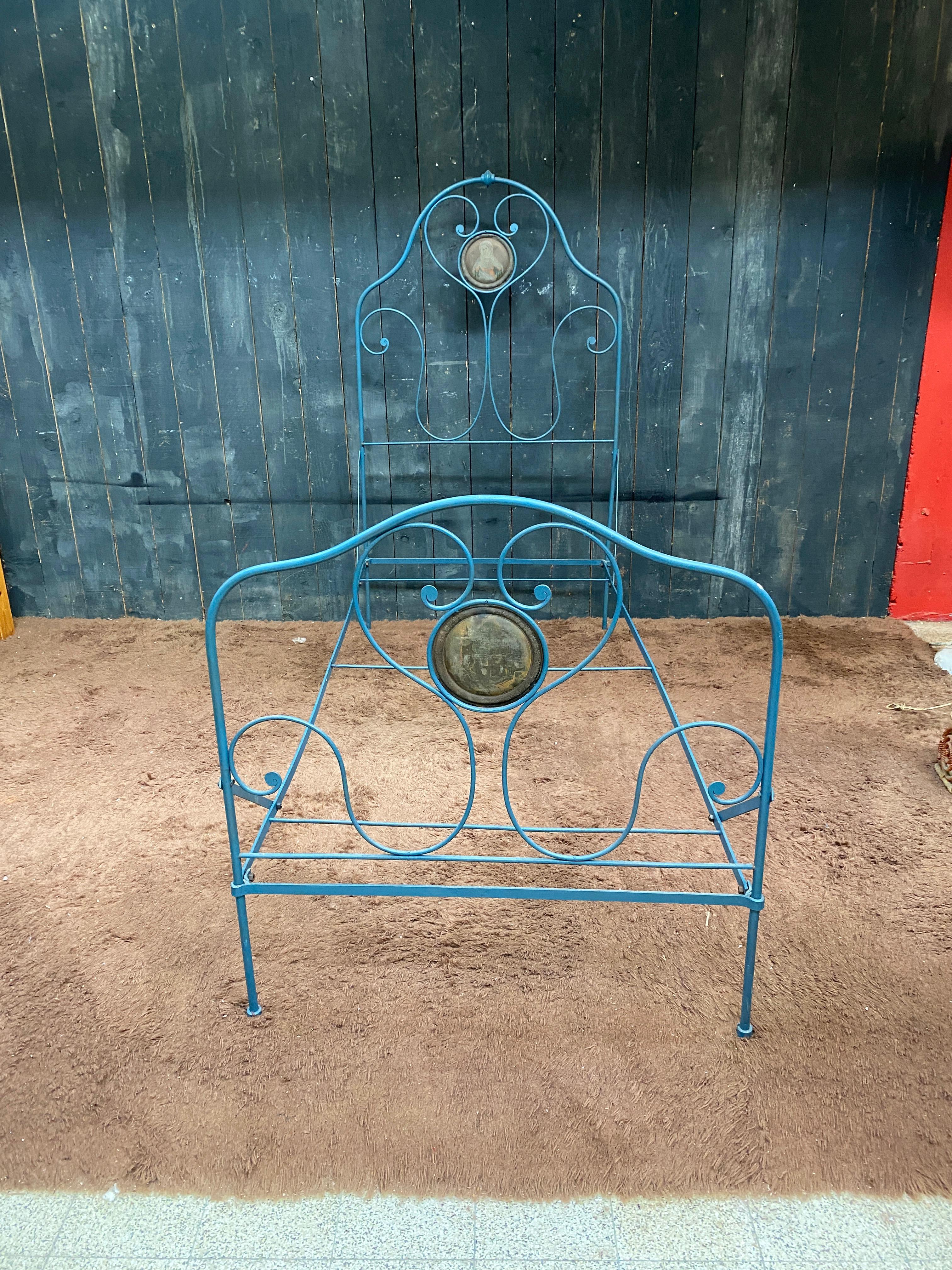 Ancien lit en fer forgé laqué, provenant d'une congrégation religieuse, décoré de deux médaillons peints.
pour un matelas de 203 x 90 cm 
manque de peinture, notamment sur les médaillons