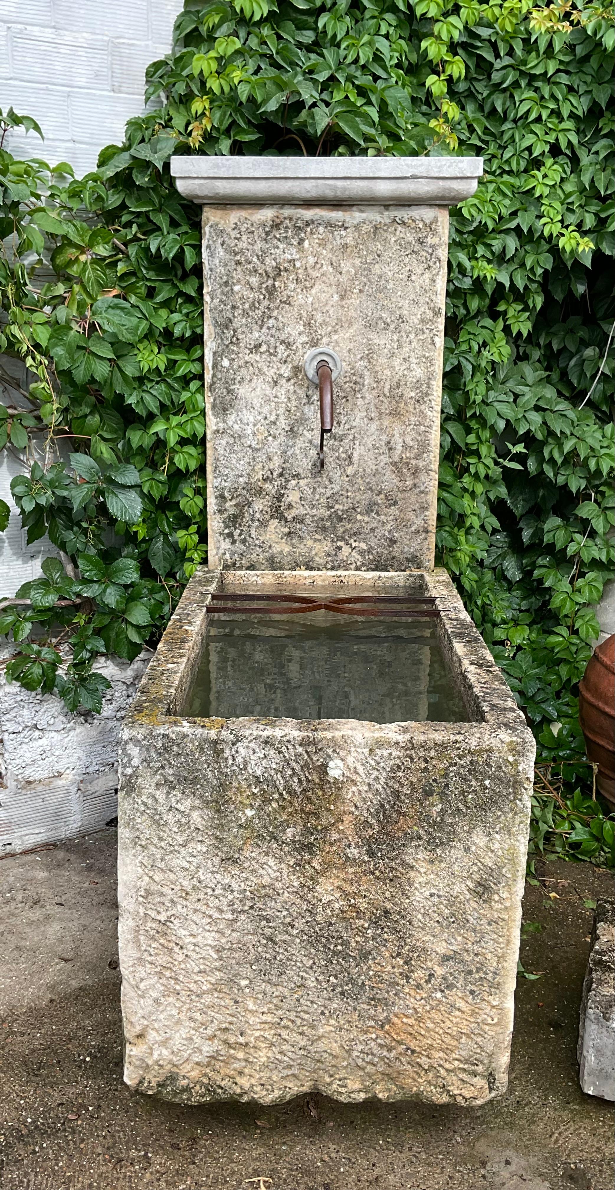 Dieser bezaubernde Brunnen aus antiken Steinelementen mit seinen Eisenbeschlägen und dem Wasserstrahl passt gut ins Haus und lehnt sich an eine Wand, wobei die Zeit ihre Spuren mit einer schönen Patina hinterlassen hat. Es wird ein zeitloses