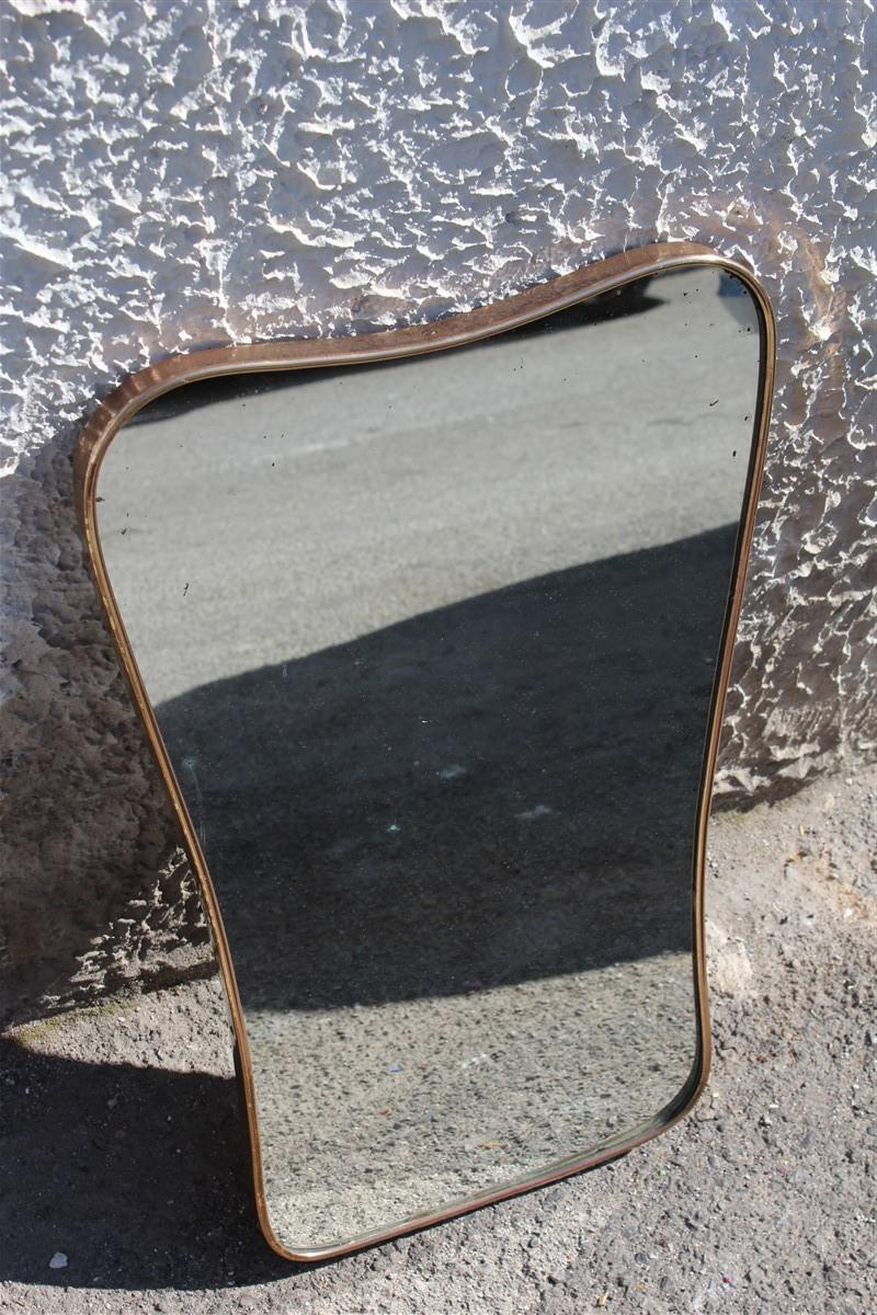 Old midcentury Italian mirror shaped in gold brass 1950 Italian design.
Measures: Upper width 39 cm, lower width 31 cm, thickness 2.5 cm.