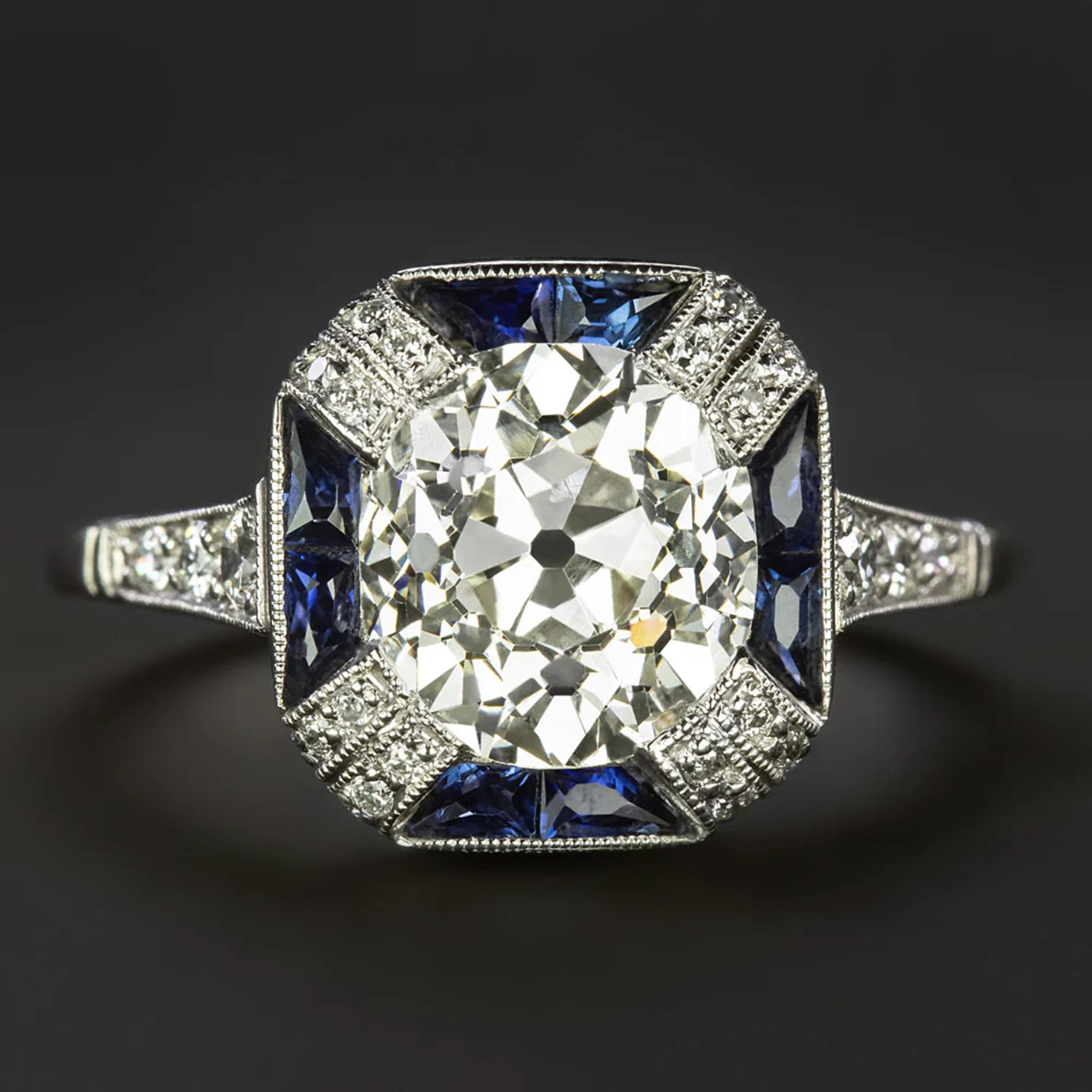 This vintage style diamond ring is impressive in size with a gorgeously detailed Art Deco style design! The true antique 2.47ct old mine cut center diamond is framed by rich blue French cut sapphires for a bold pop of color and