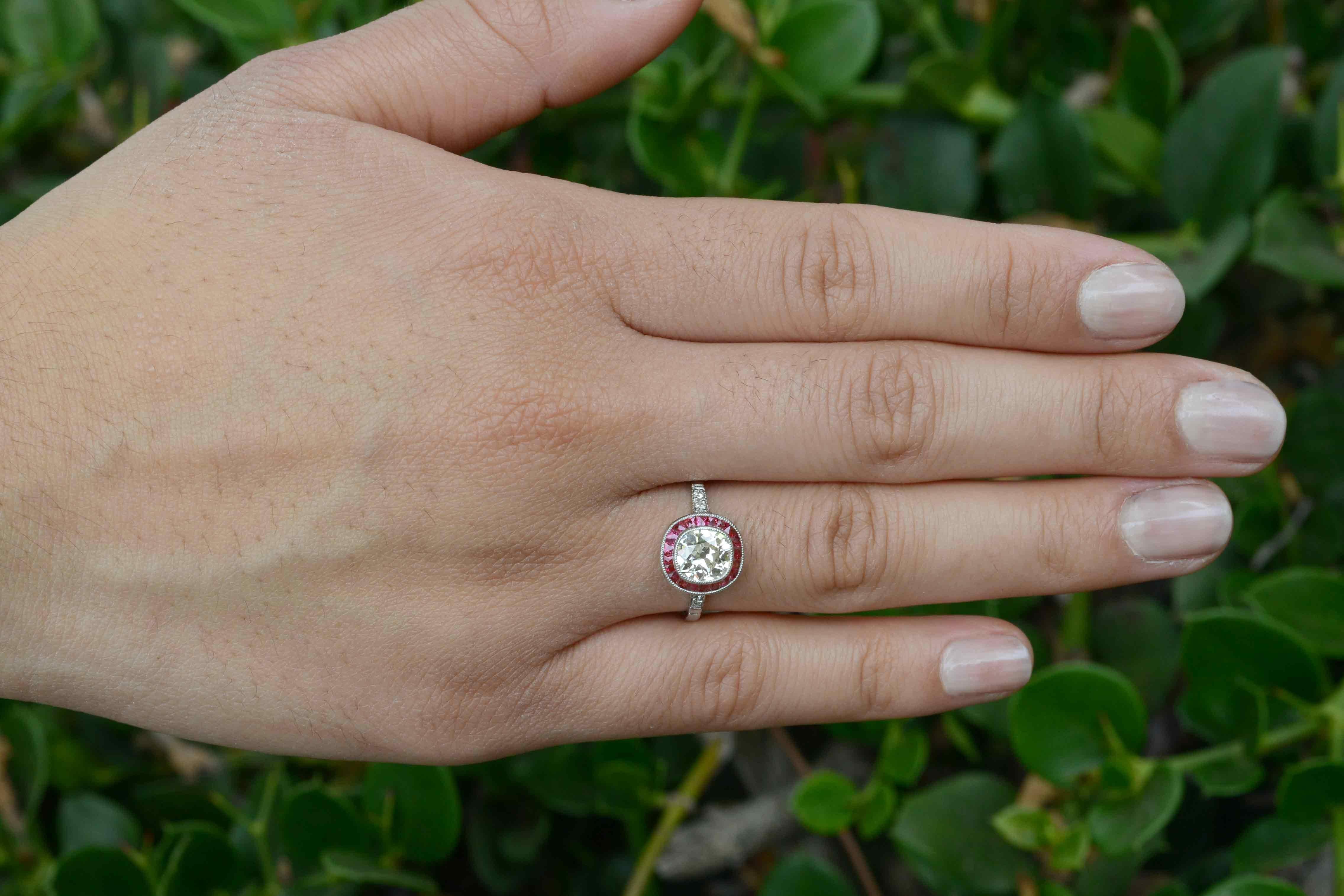 This antique cushion cut diamond engagement ring boasting a 1.08 carat old mine diamond. The chunky facets of this gem exploding with a fire unlike new, factory produced stones. And the French cut ruby halo, though! The 