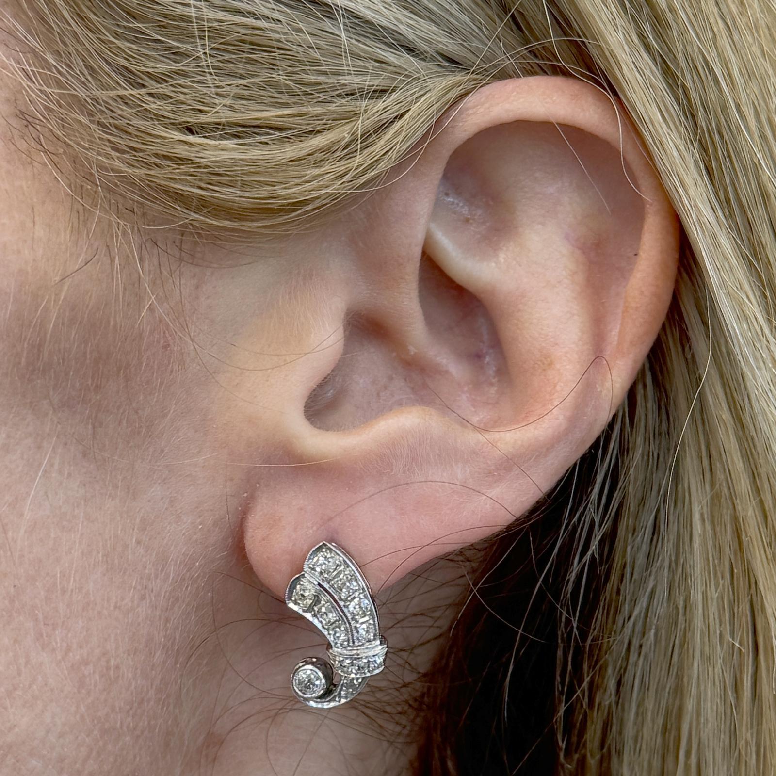These captivating antique earrings feature old mine cut and old European cut diamonds, set in 14K white gold. The earrings are designed with a graceful swirl drop shape, adding movement and elegance to the overall design. The 24 diamonds, totaling
