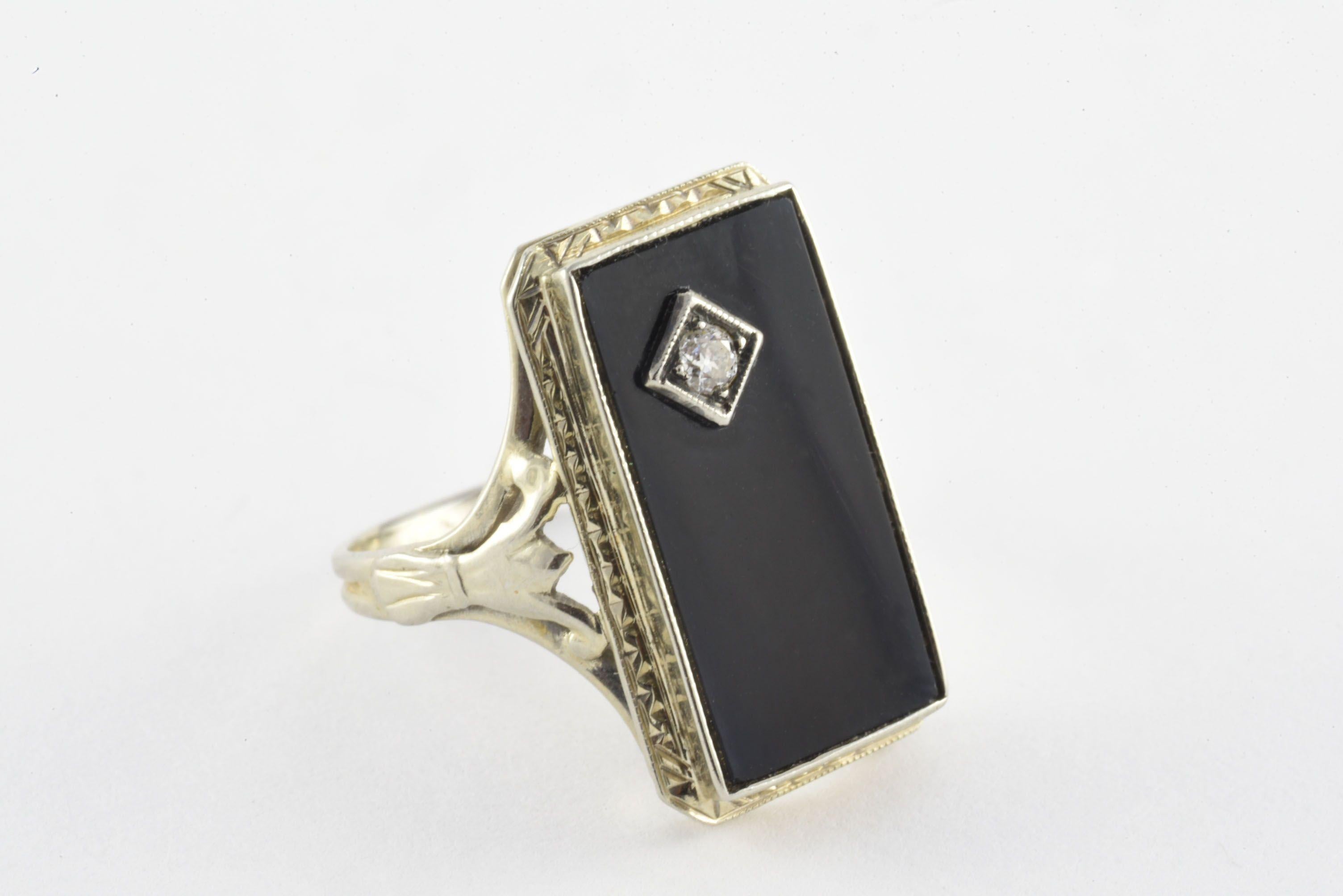 An Old Mine cut diamond weighing 0.10 carats, F-G color, VS clarity sparkles in the corner of a rectangular-shaped onyx plaque measuring 18x10mm and mounted in 18kt white gold.
