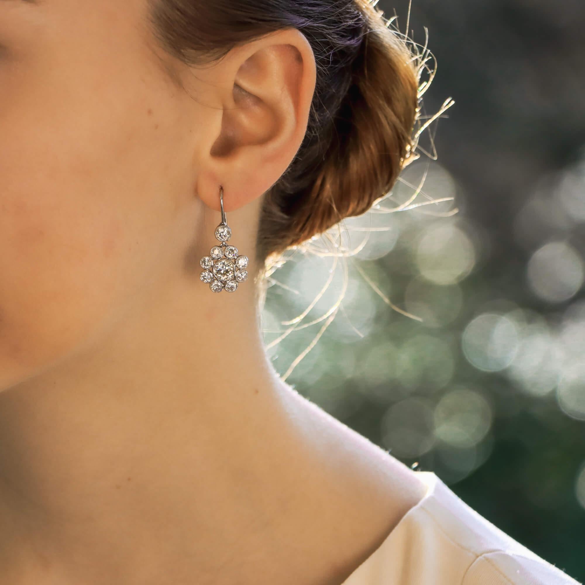 A beautiful pair of floral old mine cut diamond earrings set in platinum. 

Each earring is centrally set with a beautiful old mine cut diamond of a substantial size. These diamonds are grain set in a delicate yet secure platinum setting and