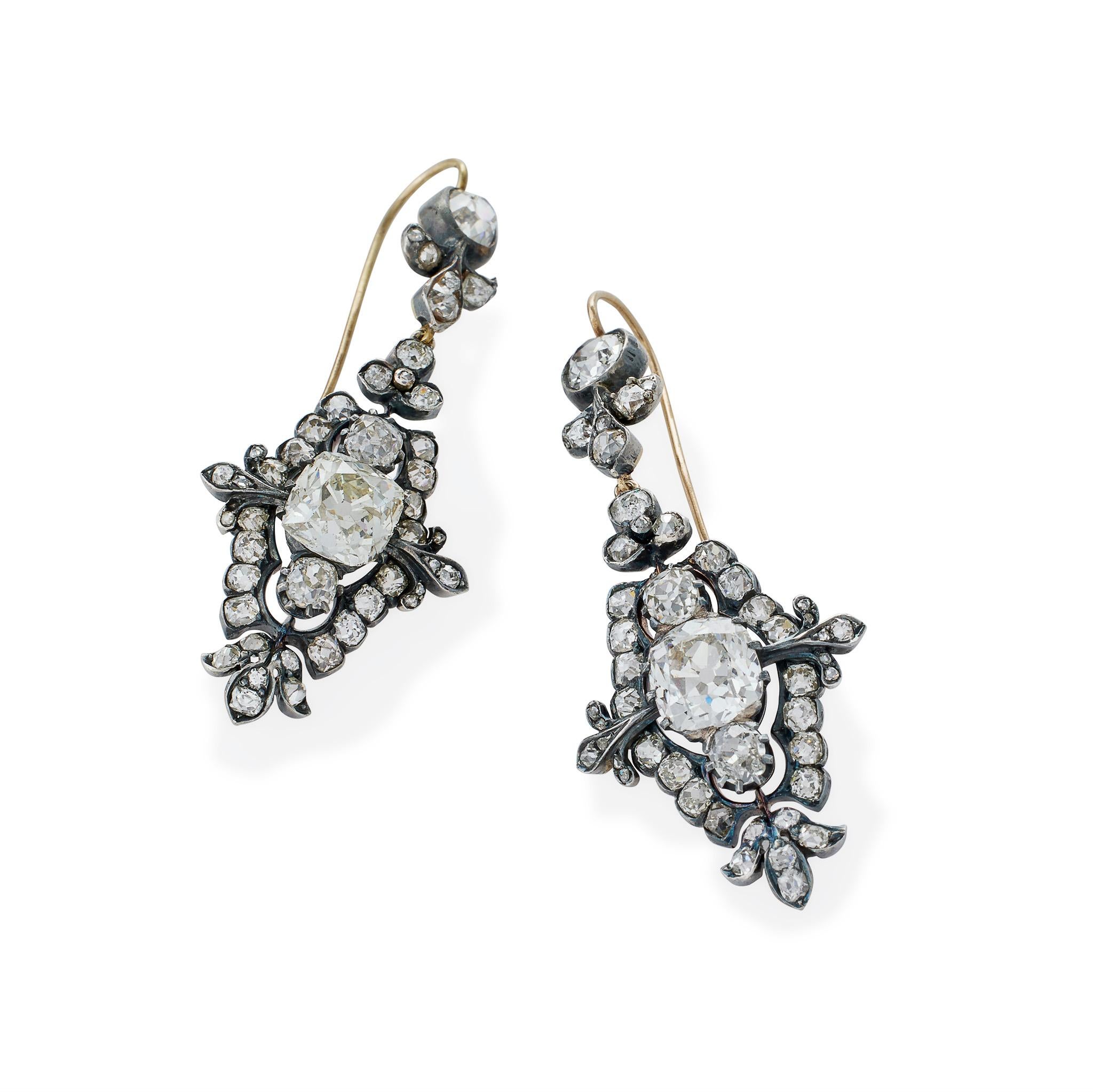 Created circa 1870, these flexibly-set old mine-cut diamond pendant earrings are mounted in silver-topped 18K gold. Set with 96 old mine-cut diamonds, with an approximate total weight of 13.00 carats, each circular top is joined by stylized foliate