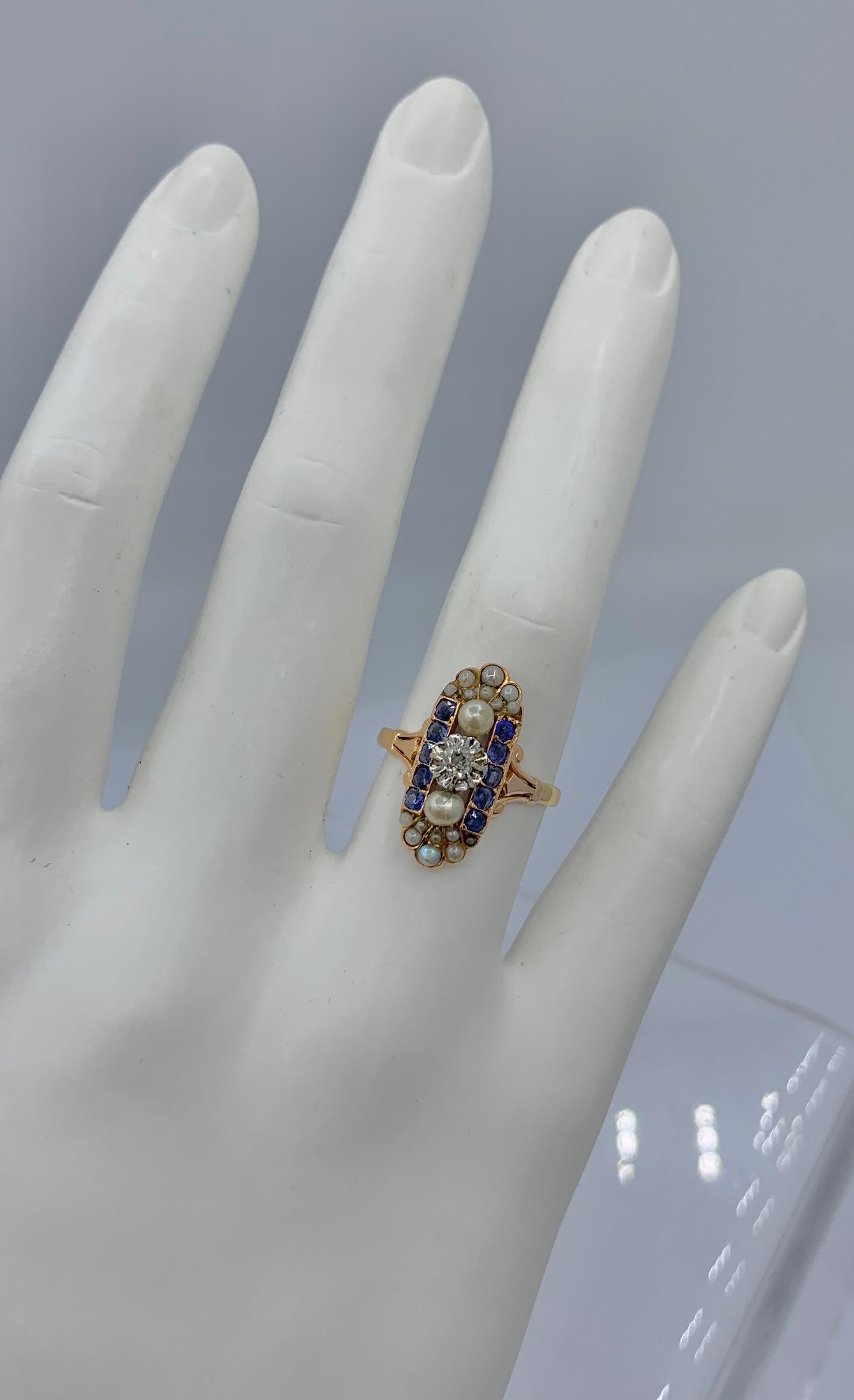 This is an absolutely stunning Old Mine Cut Diamond, Natural Sapphire and Pearl, Platinum and Gold Antique Art Deco - Victorian Wedding Engagement Ring.  The oval panel design in Platinum is gorgeous.   In the center of the ring is a sparkling Old