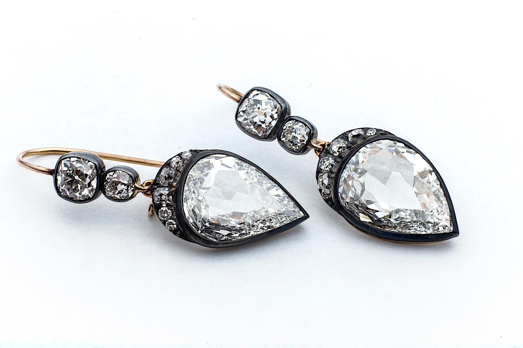 Elegantly subtle yet sensually dazzling, these inverted pear shaped diamonds are crowned with a crescent of old mine cut  diamonds dropping from two cushion cut diamonds.  Framed in antiqued gold and silver mountings, these handmade earrings