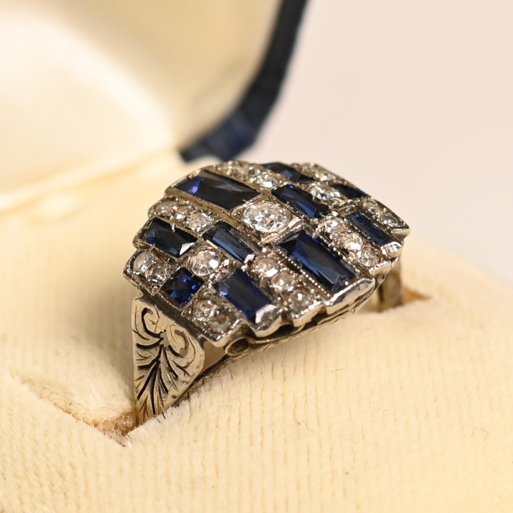 Cette exquise bague ancienne, fabriquée à la main à l'époque de l'Arte Antiques vers 1920, met en valeur un captivant diamant taillé dans une mine ancienne en son centre. Le diamant est encadré par une disposition géométrique frappante de diamants