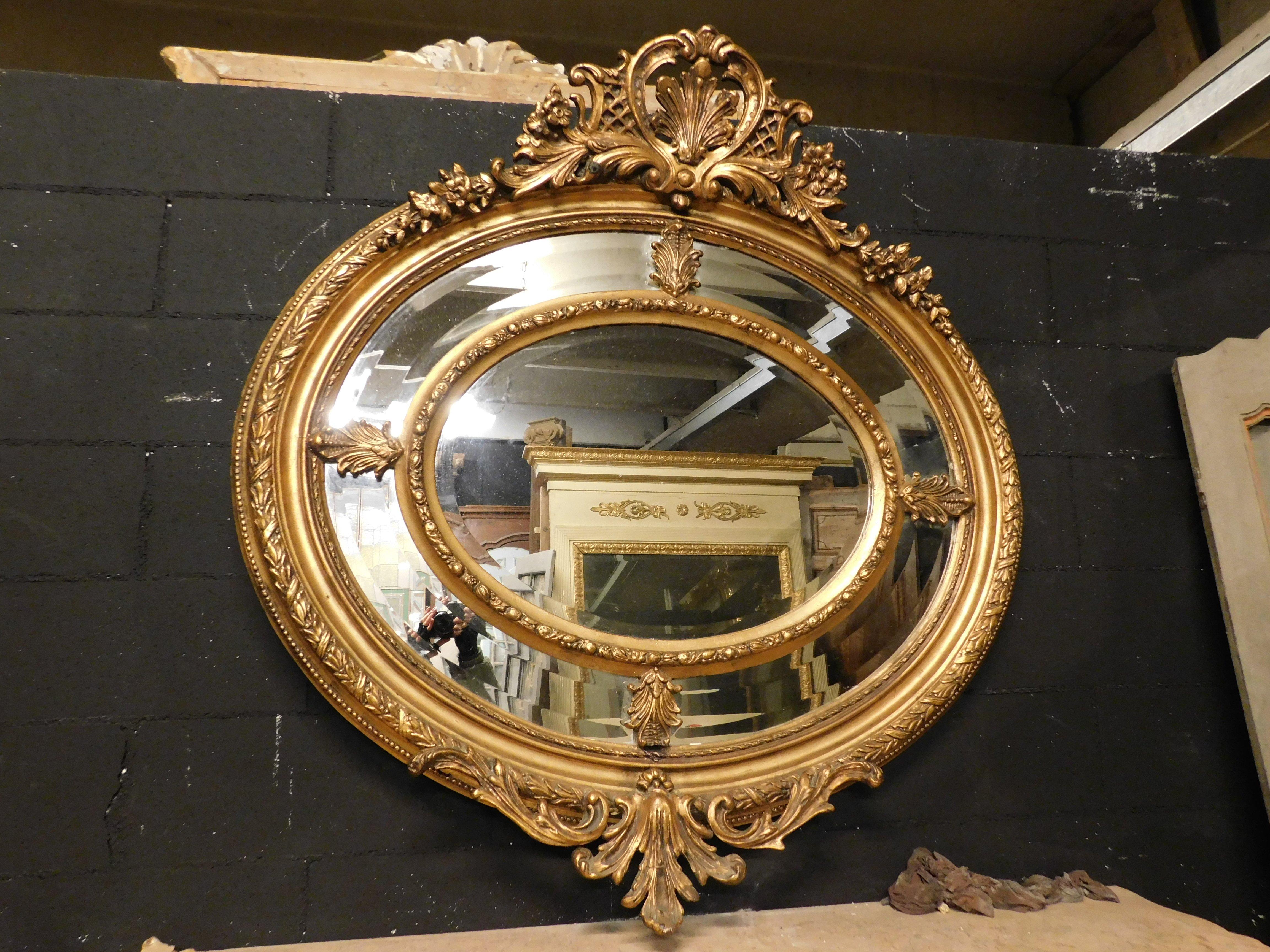 Antique wall mirror in gilded and richly carved wood, oval shape with carved and protruding cornices, built in France in the 19th century, particular double row of mirrors and frames, maximum external measurement cm w 125 x H 130.
​