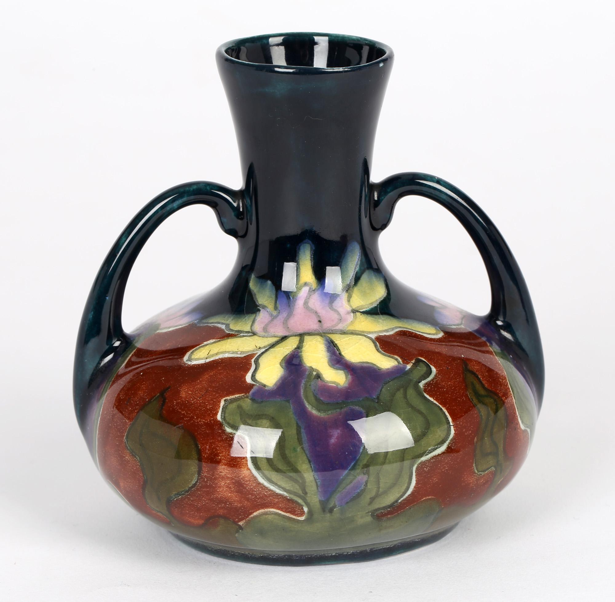 A stylish Austrian Art Nouveau twin handled art pottery vase hand painted with floral designs and made at Old Moravian Pottery around 1906. The squat rounded vase is lightly potted and hand decorated in colored enamels with painted marks to the base