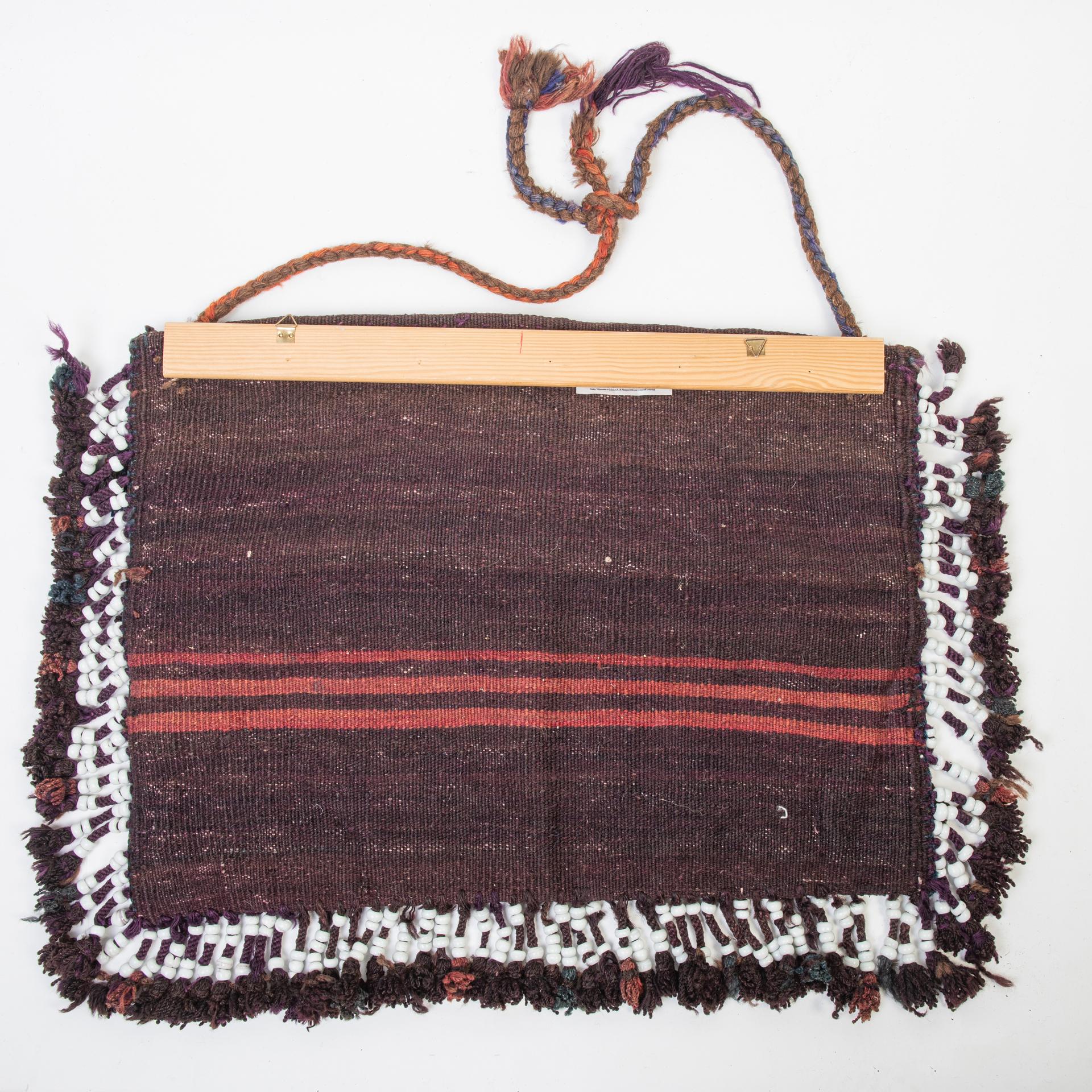 nr. 1375 - Old nomadic bag, woven by hand and decorated with rich fringes in white ceramic rings.  I fixed it on a wooden rod to hang it on the wall: it can become a comfortable bag for newspapers or other.
To hange on the sides of sofa or