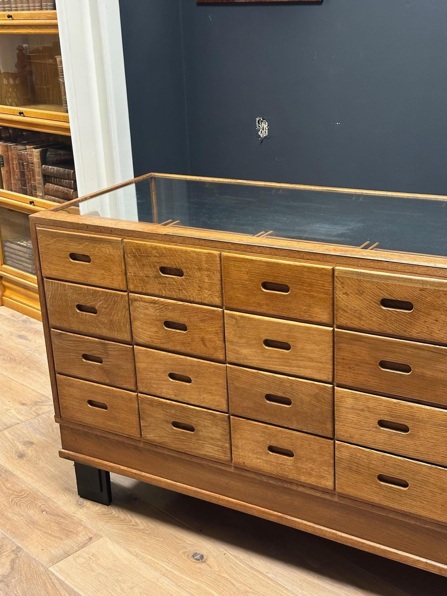 Beautiful old oak counter/display case with 24 drawers. The top drawer has an additional compartment. There's also a brass ruler on the top. Completely original and in very good condition. A display case with 24 drawers is quite rare.

Origin: