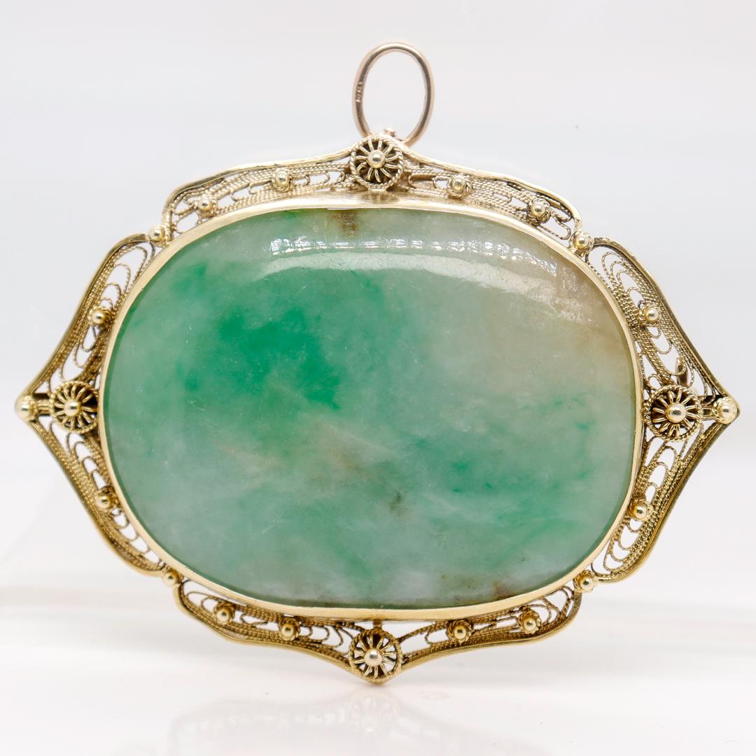 A fine old or antique Chinese gold and jade convertible brooch/pendant.

With a large mottled green jade gemstone (so-called Moss-in-Snow jade) that is bezel-set in an ornate 14k yellow gold setting.

Set with a bar pin to the reverse for use as a