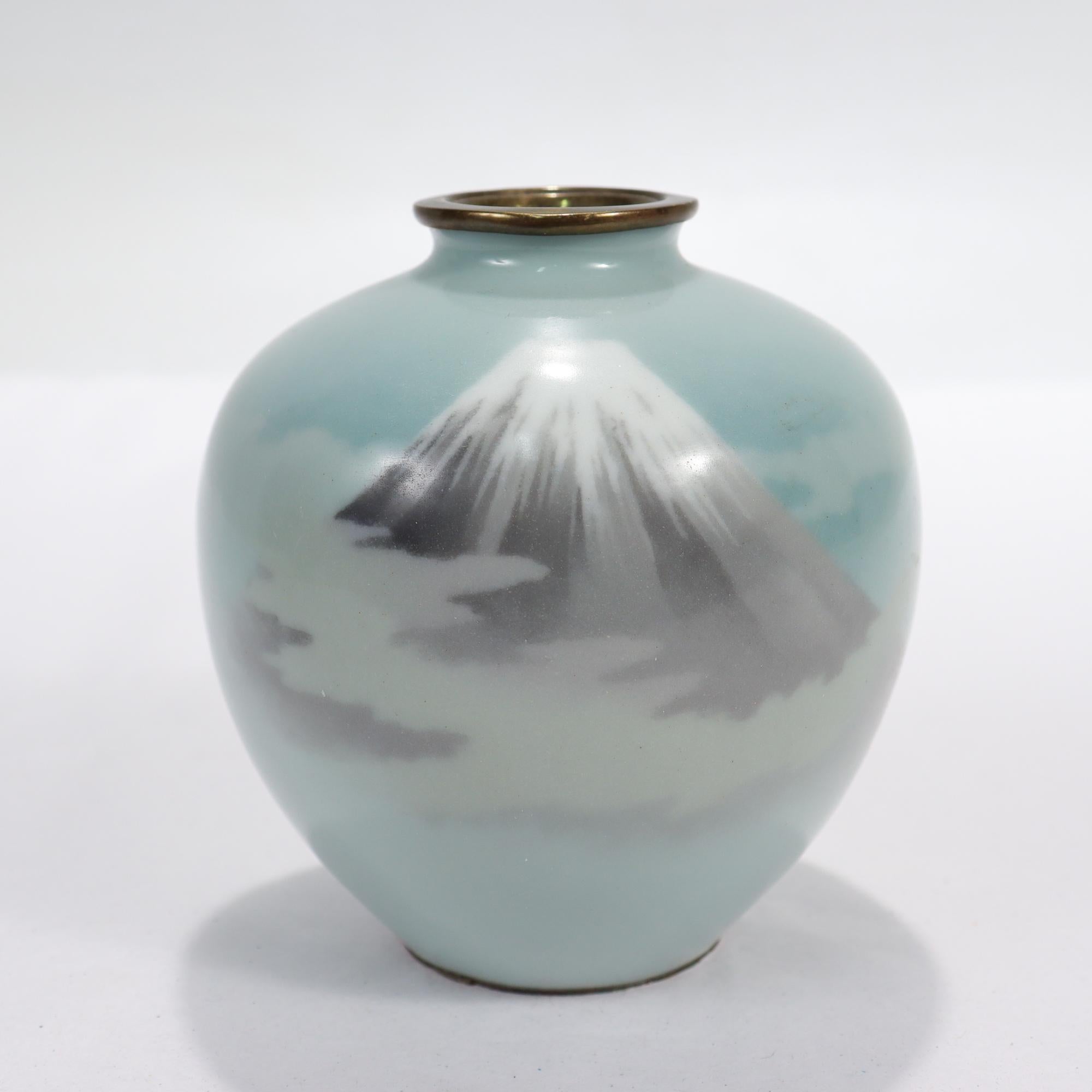 Un très beau vase ancien en émail cloisonné.

Avec une représentation du Mont Fuji enveloppé de nuages sur un fond bleu clair.

Tout simplement un joli petit vase japonais !

Date :
Fin du 19e ou début du 20e siècle

Condition générale :
Il est en