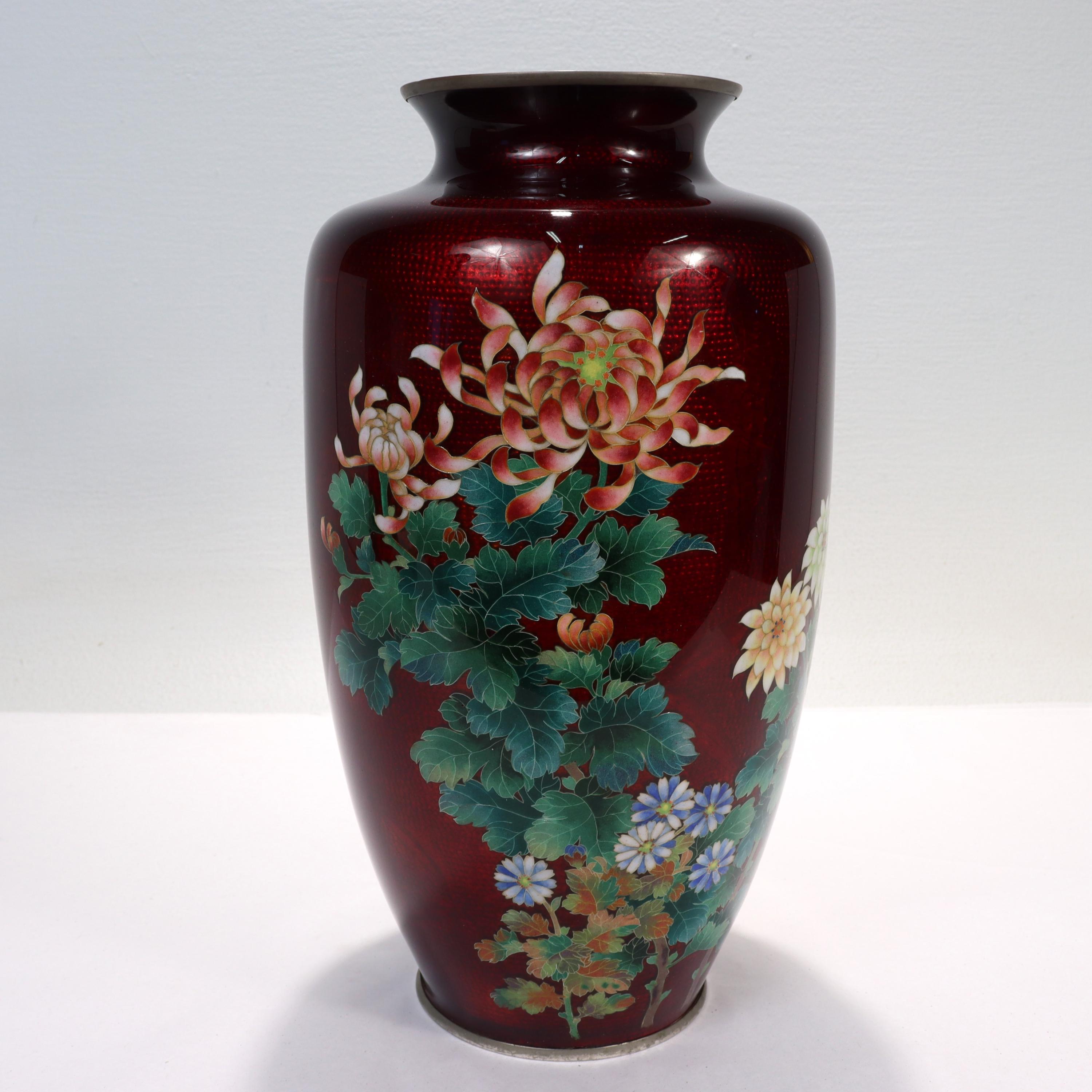 A fine antique Japanese enamel vase.

With wired cloisonne flowers against a red ginbari ground.

The ginbari technique (similar to guilloche enamel) involves flooding transparent enamel over a patterned metal surface. This creates a shiny