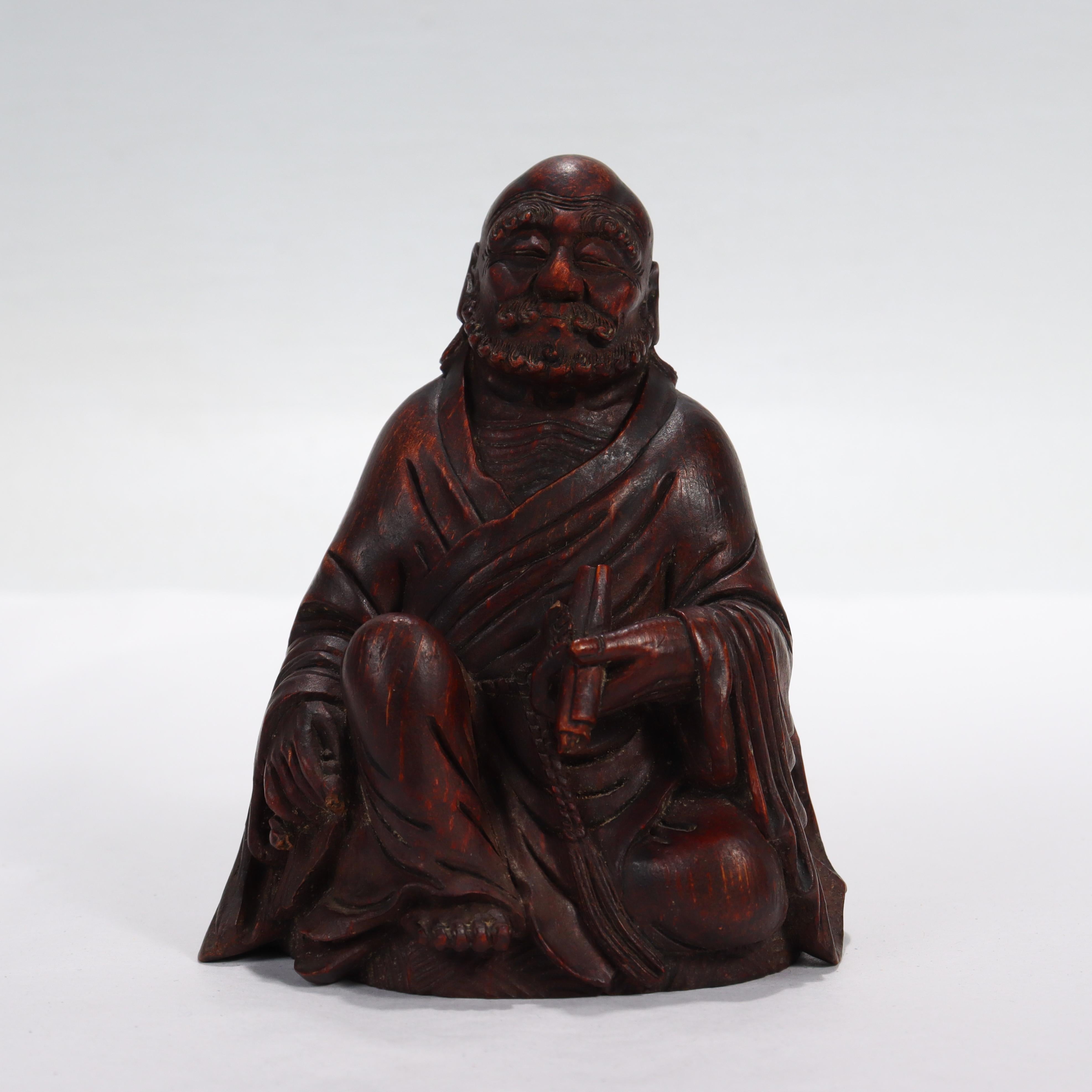 A Japanese wooden figurine of a Buddhist monk.

In the form of a seated Buddhist monk. 

He holds a scroll in his left hand, and a mala/juzu (rosary) in his right hand. Part of the mala has broken off.

Simply a great wooden figurine!

Date:
Late