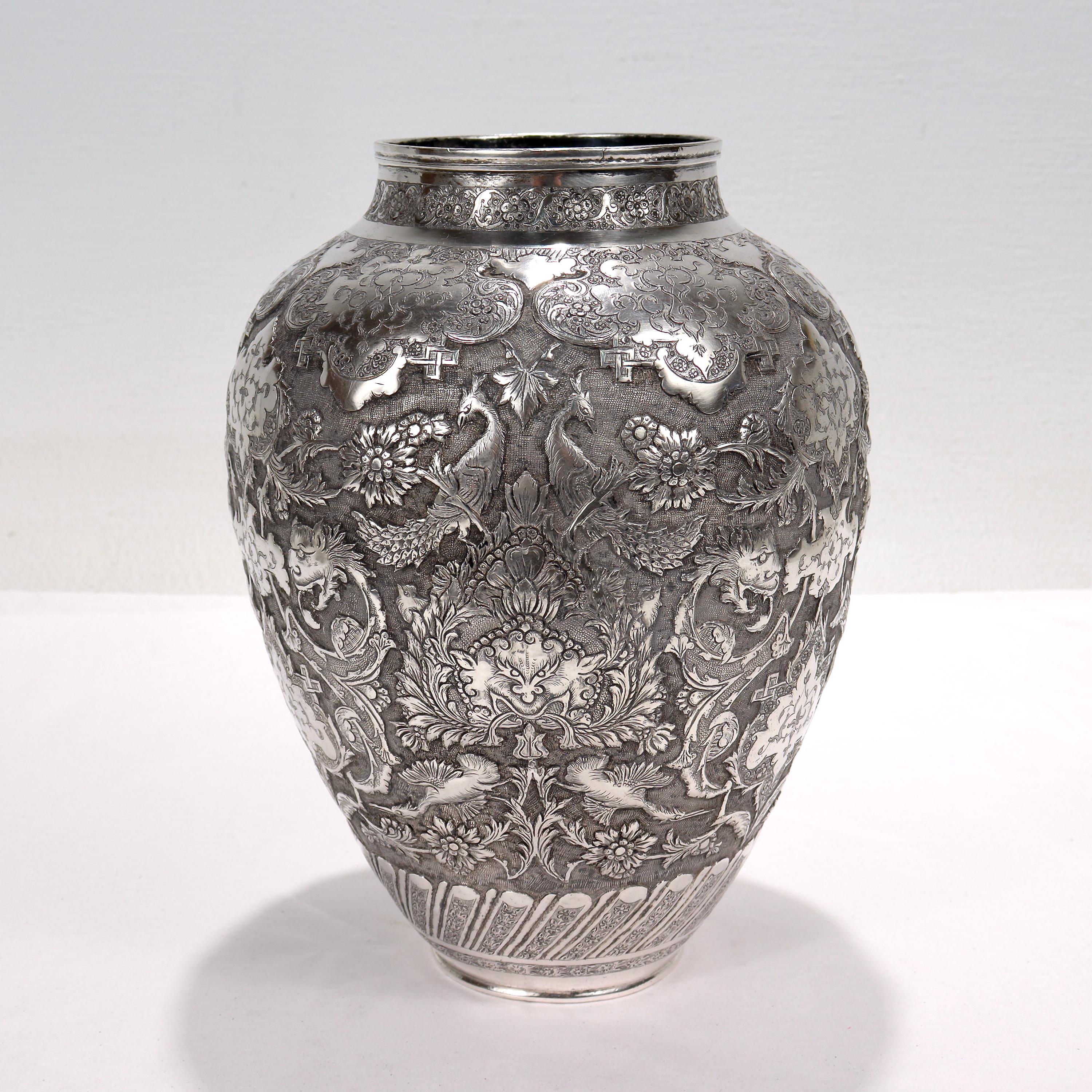 A fine Islamic silver vase.

Richly decorated with Ishafan (Eshafan) style repousse decoration throughout including gryphon heads, flowers & vines, birds of paradise, foliage, and Arabesque geometric decoration throughout. 

Signed to the base with