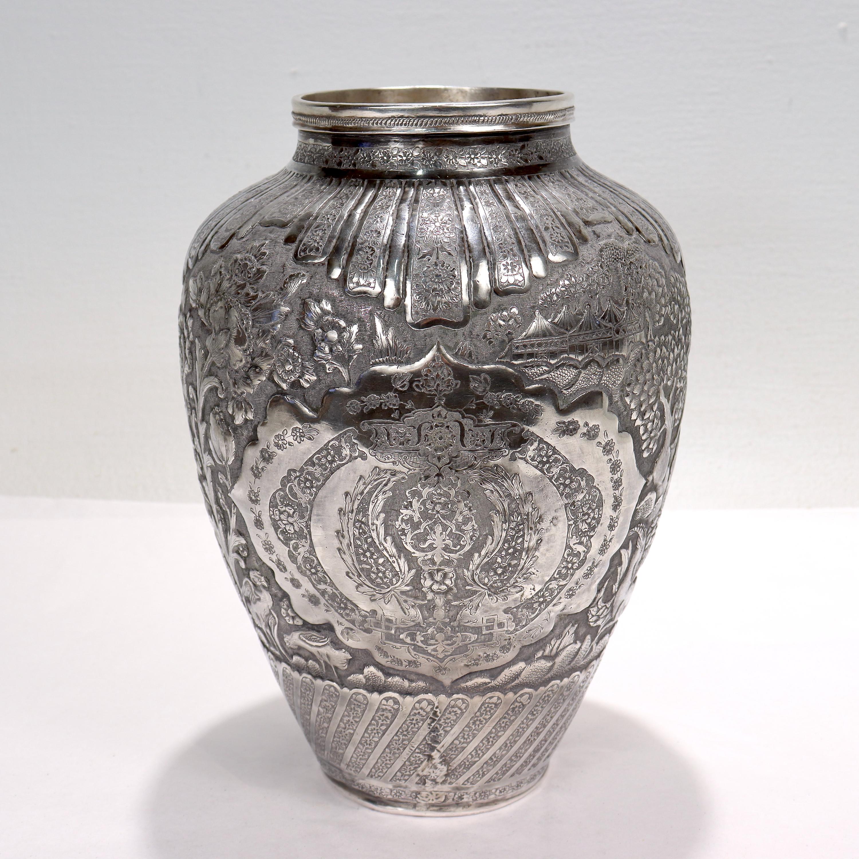 A fine old or antique Islamic silver vase.

Richly decorated with Ishafan (Eshafan) style repousse decoration throughout including gryphon heads, flowers & vines, birds of paradise, foliage, and Arabesque geometric decoration throughout. 

Signed to
