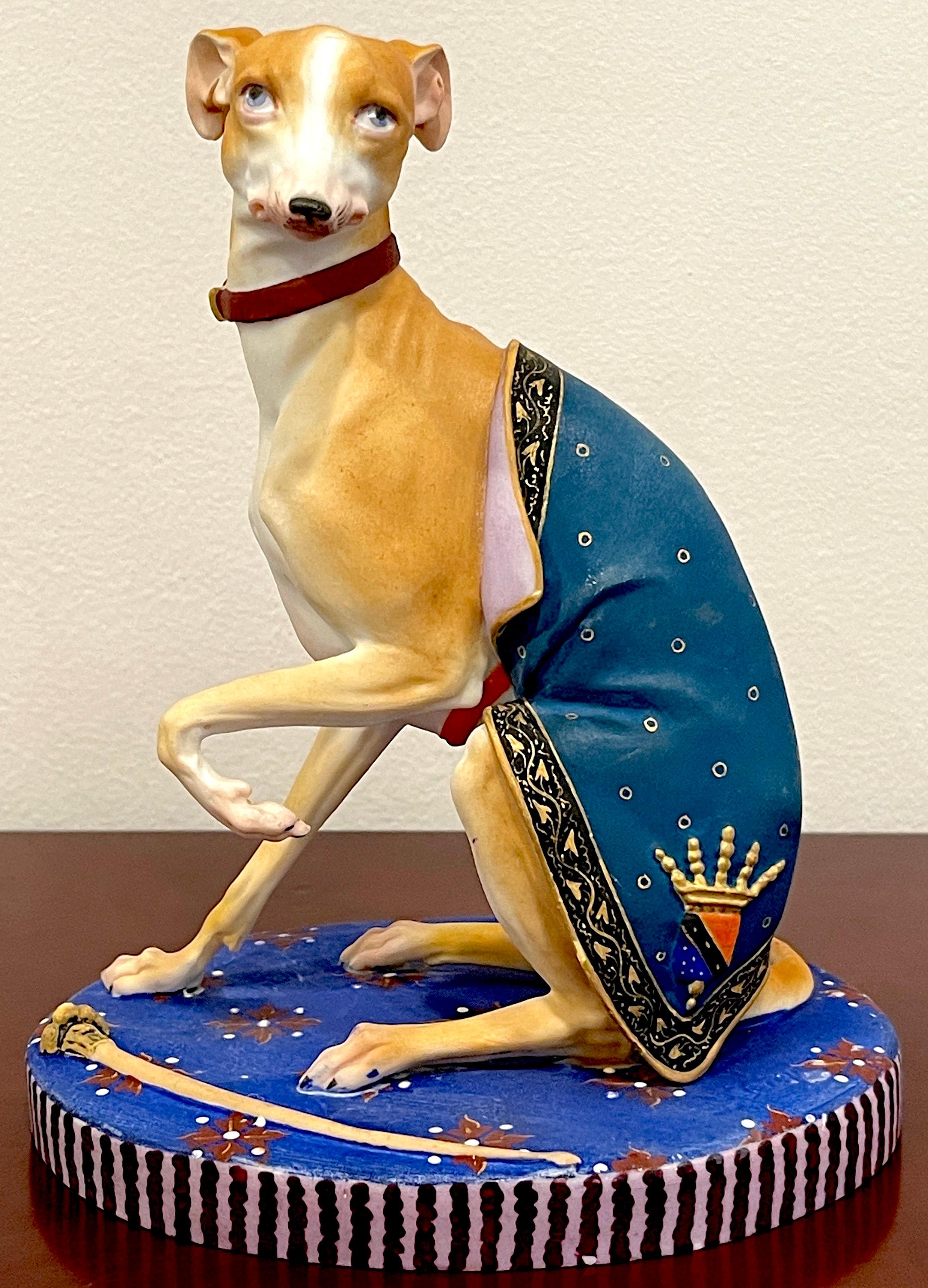 Old Paris Polychromed Biscuit Porcelain Model of Seated Draped Armorial Whippet / Greyhound
France, Circa 1880

Realistically modeled figure of a seated Whippet/ Greyhound, draped  with an armorial crested blanket, raised on an oval base with a