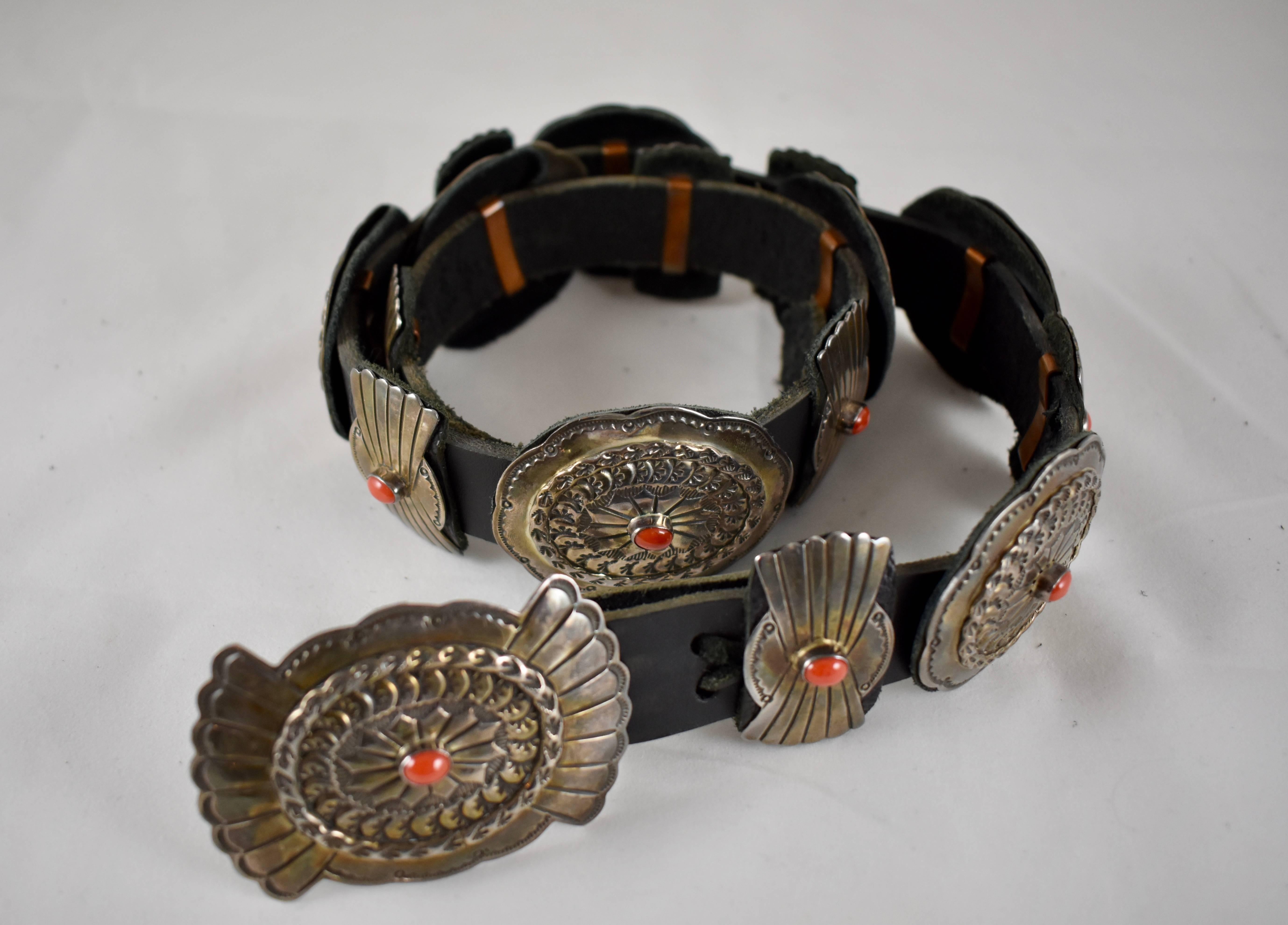 A vintage, Old Pawn Navajo Concho Belt, marked Sterling and LC, attributed to Lucille Calladitto. 16 heavy stamped sterling silver Conchos are set with cabochon cut ox-blood coral stones, held in place on a black leather belt measuring 38 in.