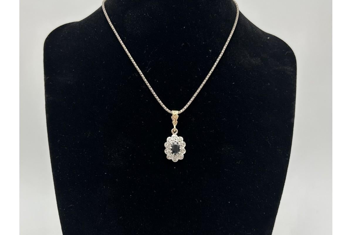Pendentif classique ancien et élégant en or blanc et jaune 0,375 avec un saphir ovale bleu foncé pesant 1,00ct entouré de 10 diamants d'un poids total de 0,10ct.

Un classique intemporel de l'élégance.

Origine : Grande-Bretagne, milieu du XXe